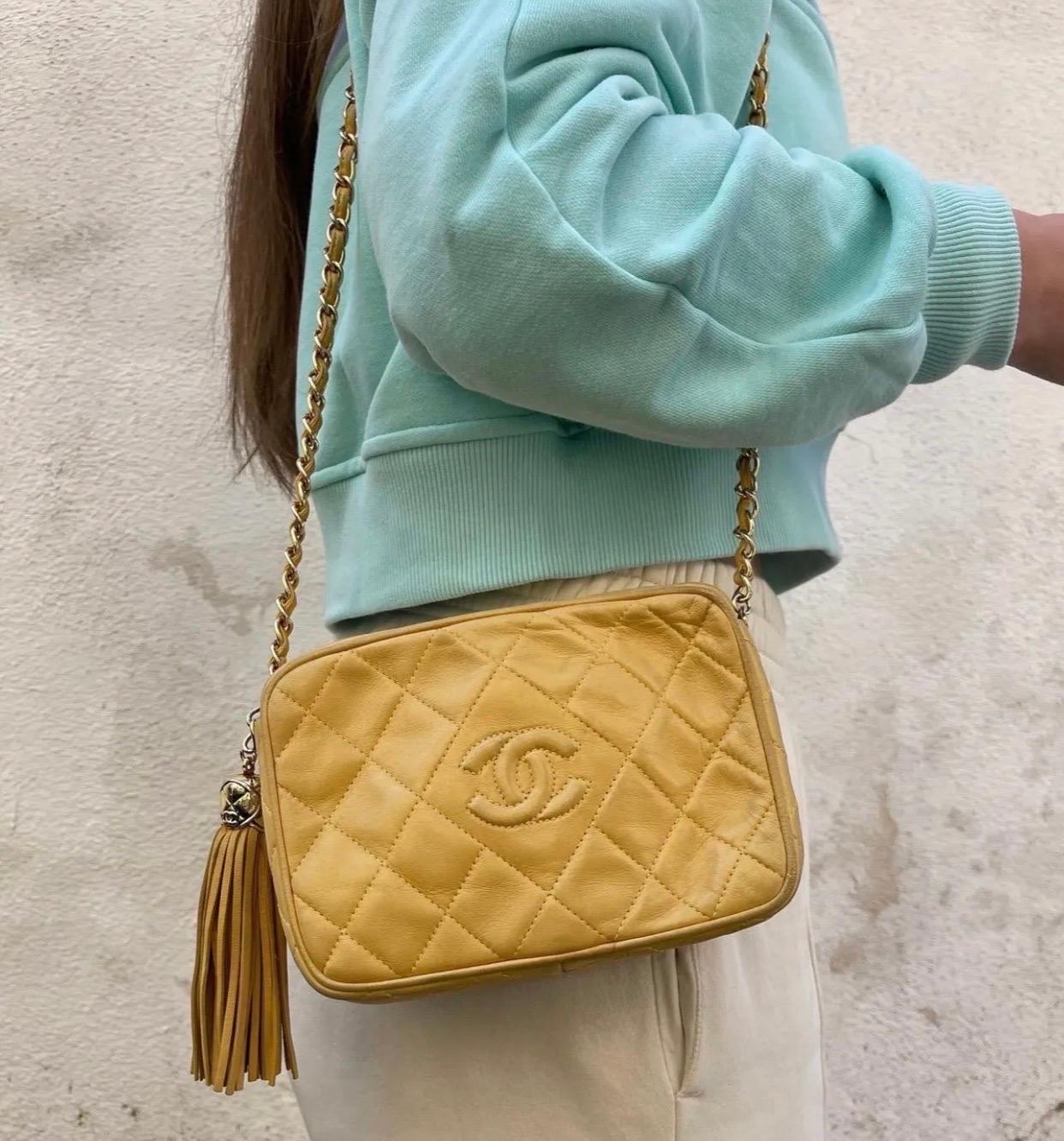 

Borsa firmata Chanel, modello camera bag, realizzata in morbida pelle gialla con hardware dorati. Dotata di una chiusura con cerniera e nappina in pelle. Munita di tracolla in pelle e catena intrecciata. Internamente foderata in pelle nera,