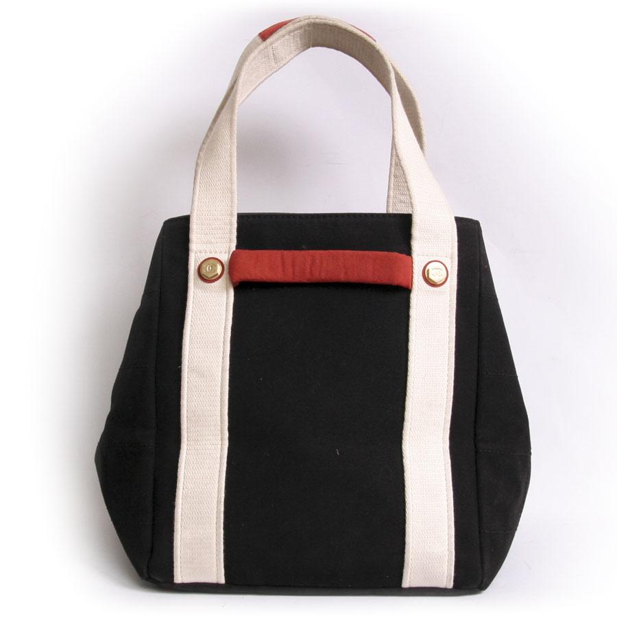 This used CHANEL canvas bag is in black, white and red canvas. It is very practical. It has a large storage space to store all your accessories. It has a double white handle. The lining is in black monogram canvas with a large zipped pocket. A small