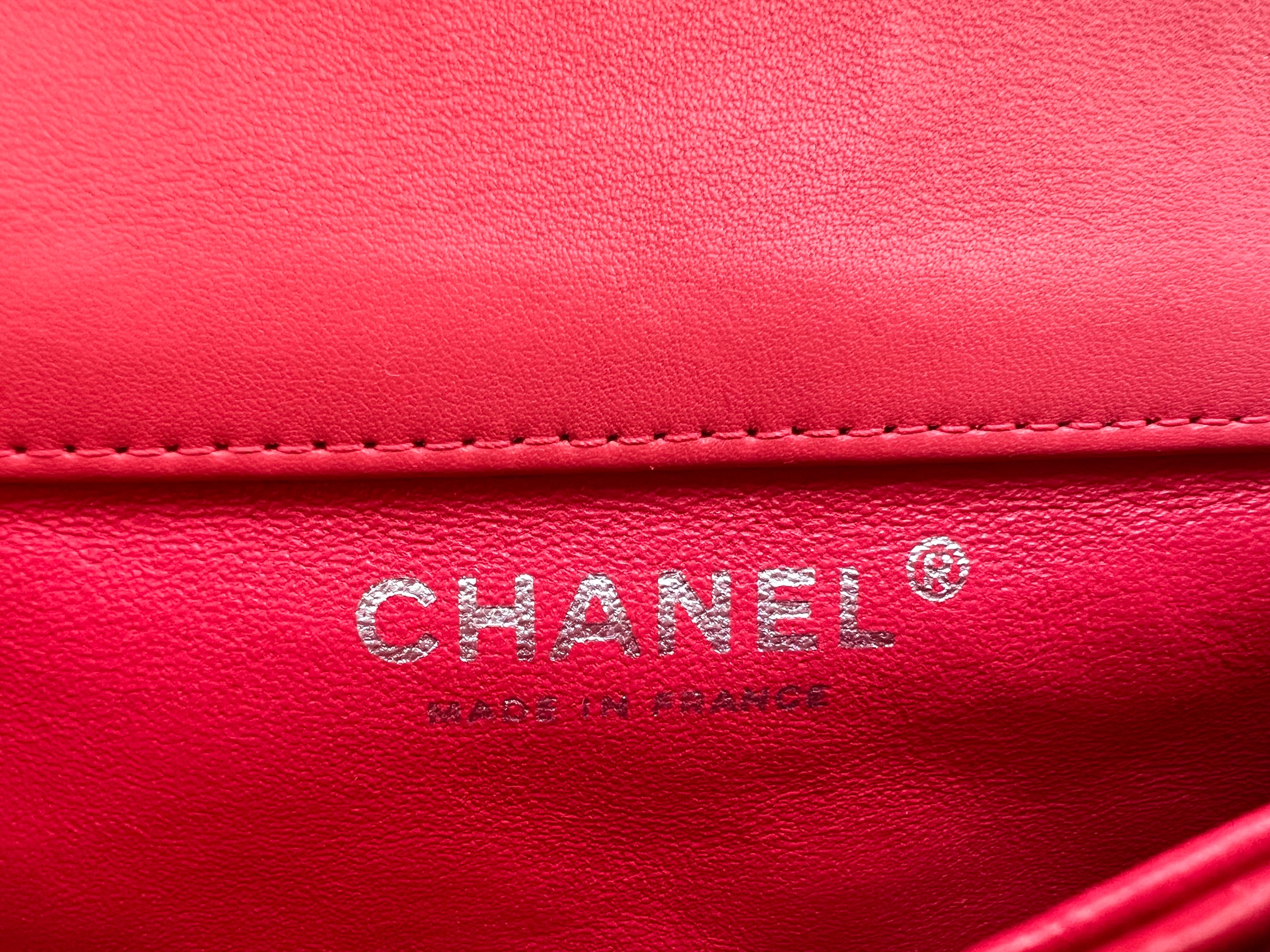 The Chanel Mini Flap in patent leather is a coveted accessory that embodies the timeless elegance and luxury associated with the Chanel brand. In a vibrant coral color and adorned with silver hardware, this particular variation exudes a bold and