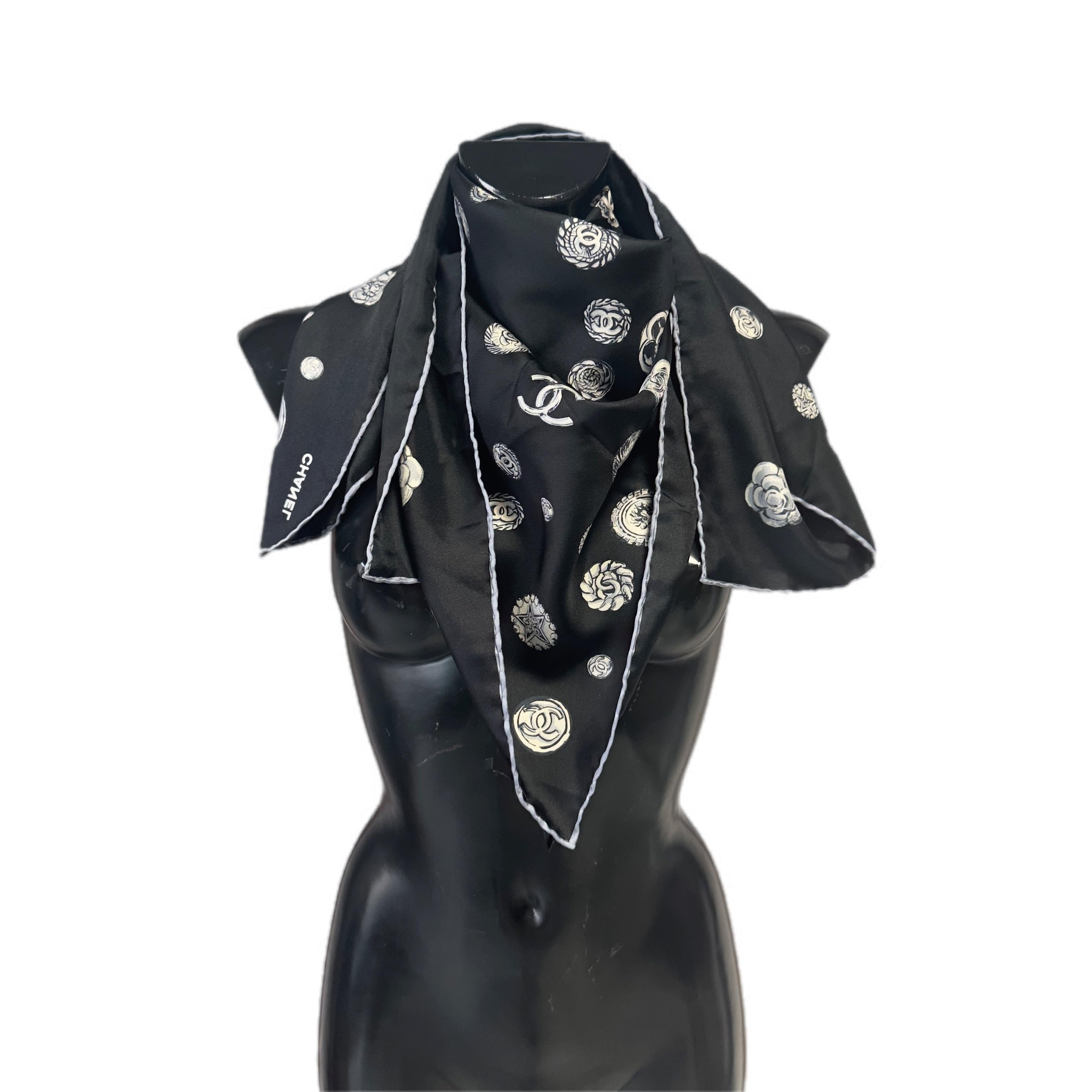 Elegante carré Chanel in pura seta (100%), 
Il foulard misura 90x90 cm ed è orlato a mano, dettaglio che ne sottolinea la qualità artigianale. Il design presenta una base nera con stampa bianca che raffigura una pioggia di bottoni iconici della