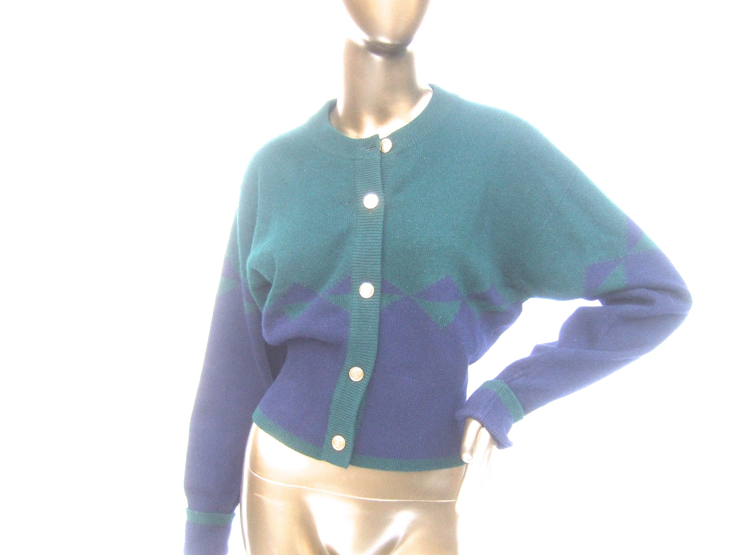 Chanel Luxurious cashmere blue & green gilt logo button cardigan c. 1990 
The stylish Chanel cardigan is constructed with plush double-ply cashmere 
The cashmere cardigan is designed with a combination of dark hunter green
cashmere juxtaposed with