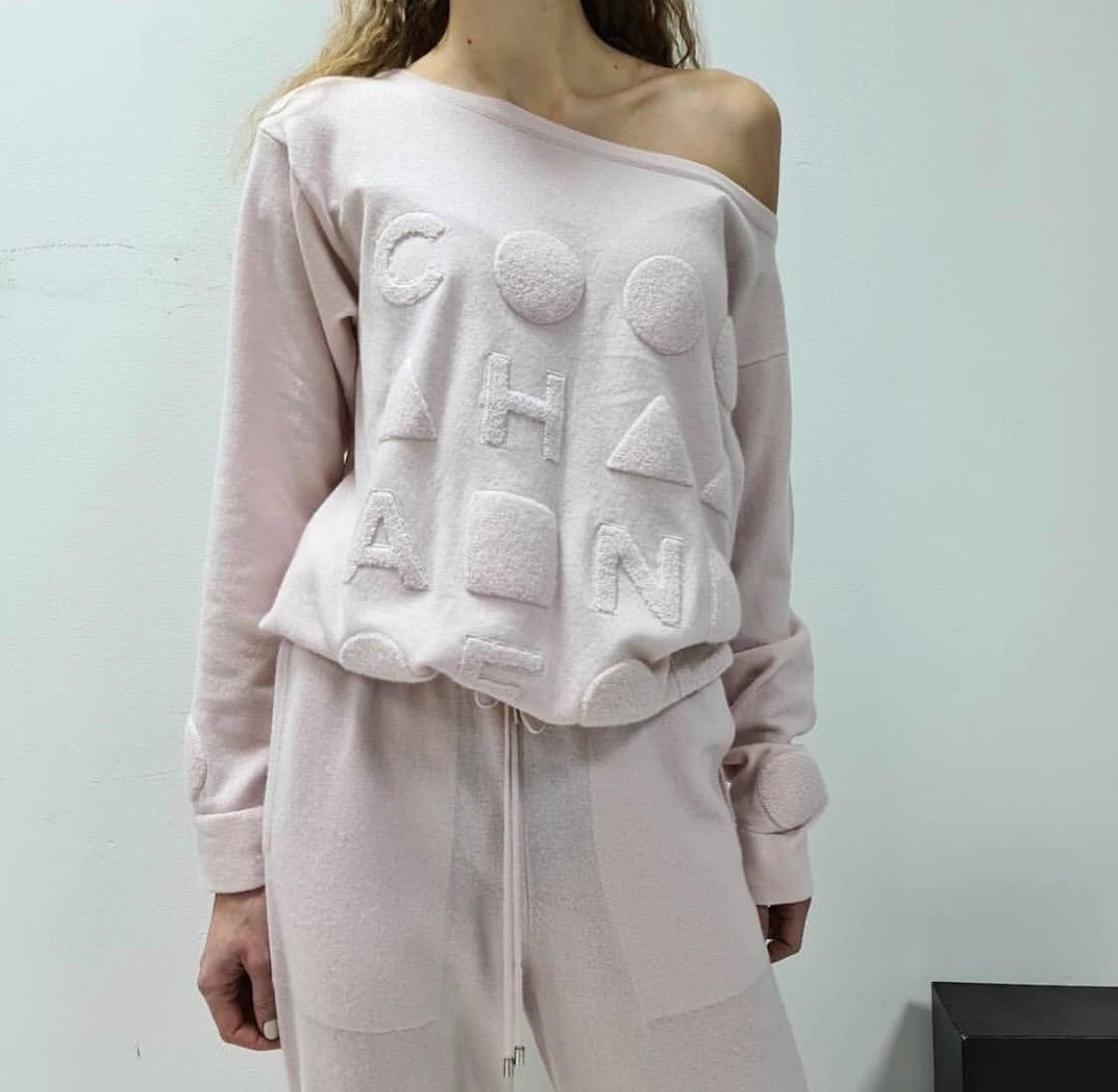 From the Spring 2013 Collection.
Baby pink Chanel cashmere lounge wear set. Sweater features bateau neck, terrycloth logo appliqué at front, tonal embroidery, drawstring at waist and rib knit trim throughout. Pants feature straight-leg silhouette,