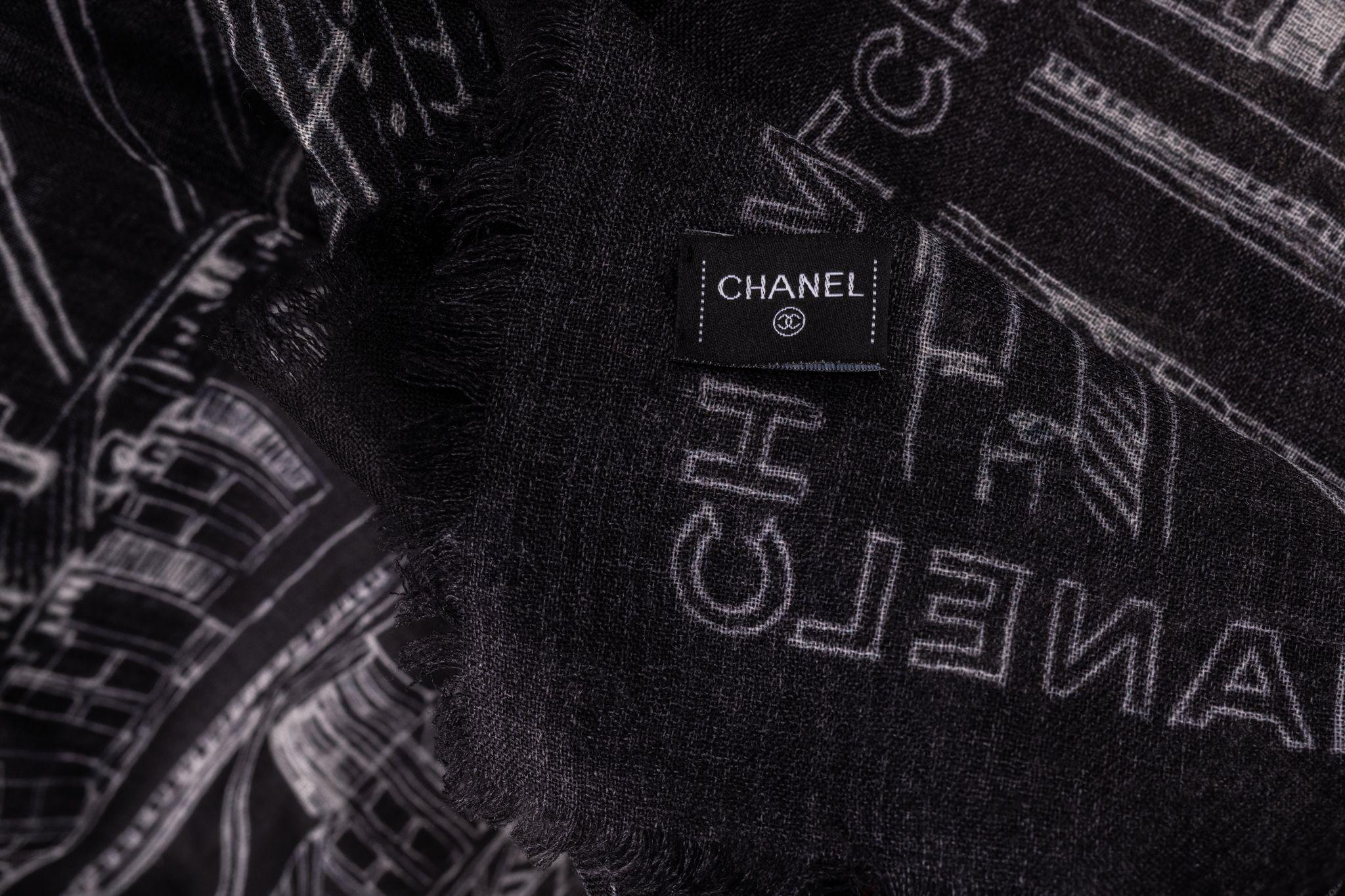 Chanel Cashmere Shawl in black featuring a print of Paris and framed with Chanel writings. In new condition.