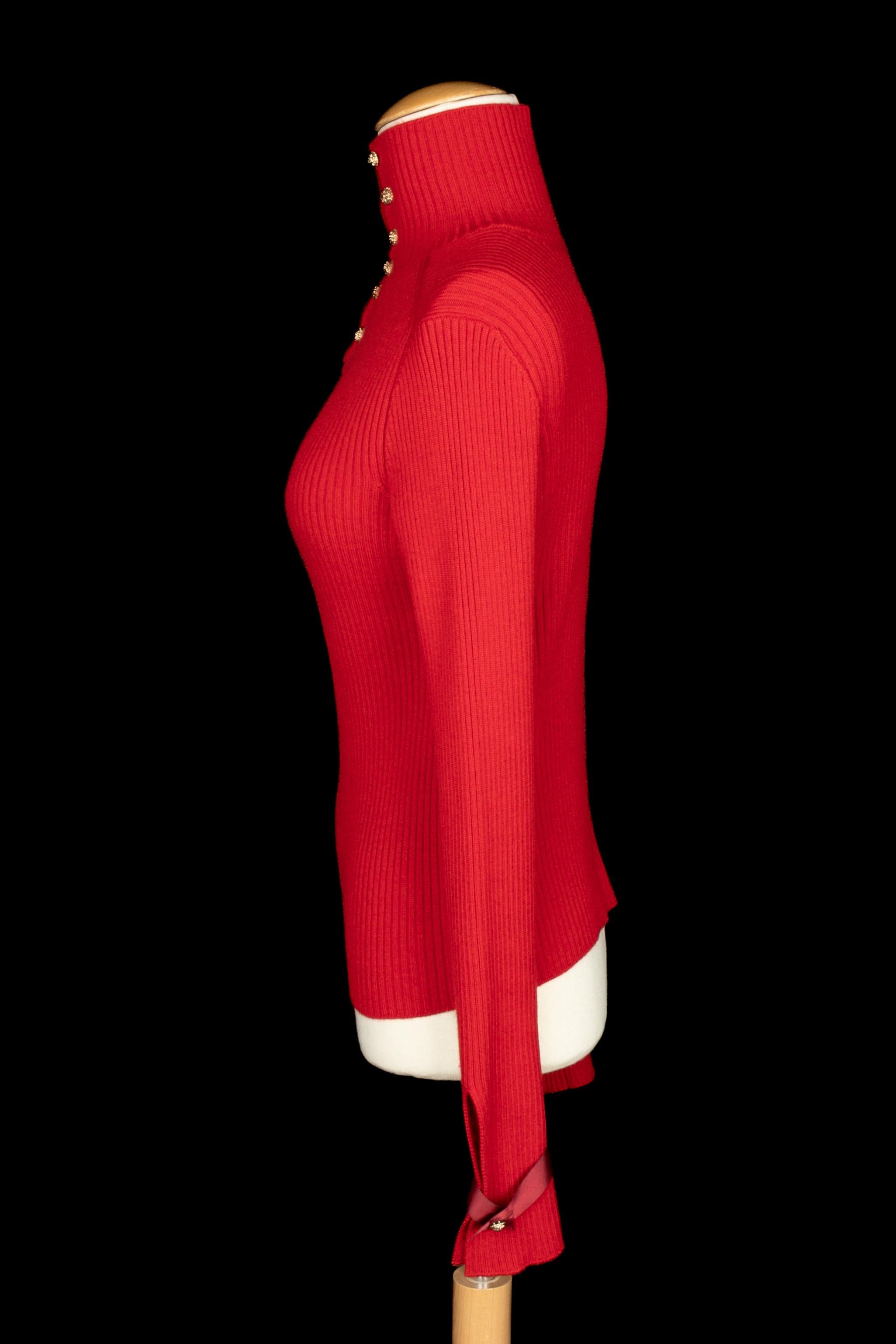 CHANEL - Pull à col roulé en cachemire rouge. Boutons à tête de lion en métal champagne. L'étiquette de la taille est manquante, il s'agit d'un 38FR.

Condit :
Très bon état.

Dimensions :
Largeur des épaules : 42 cm - Poitrine : 40 cm - Longueur