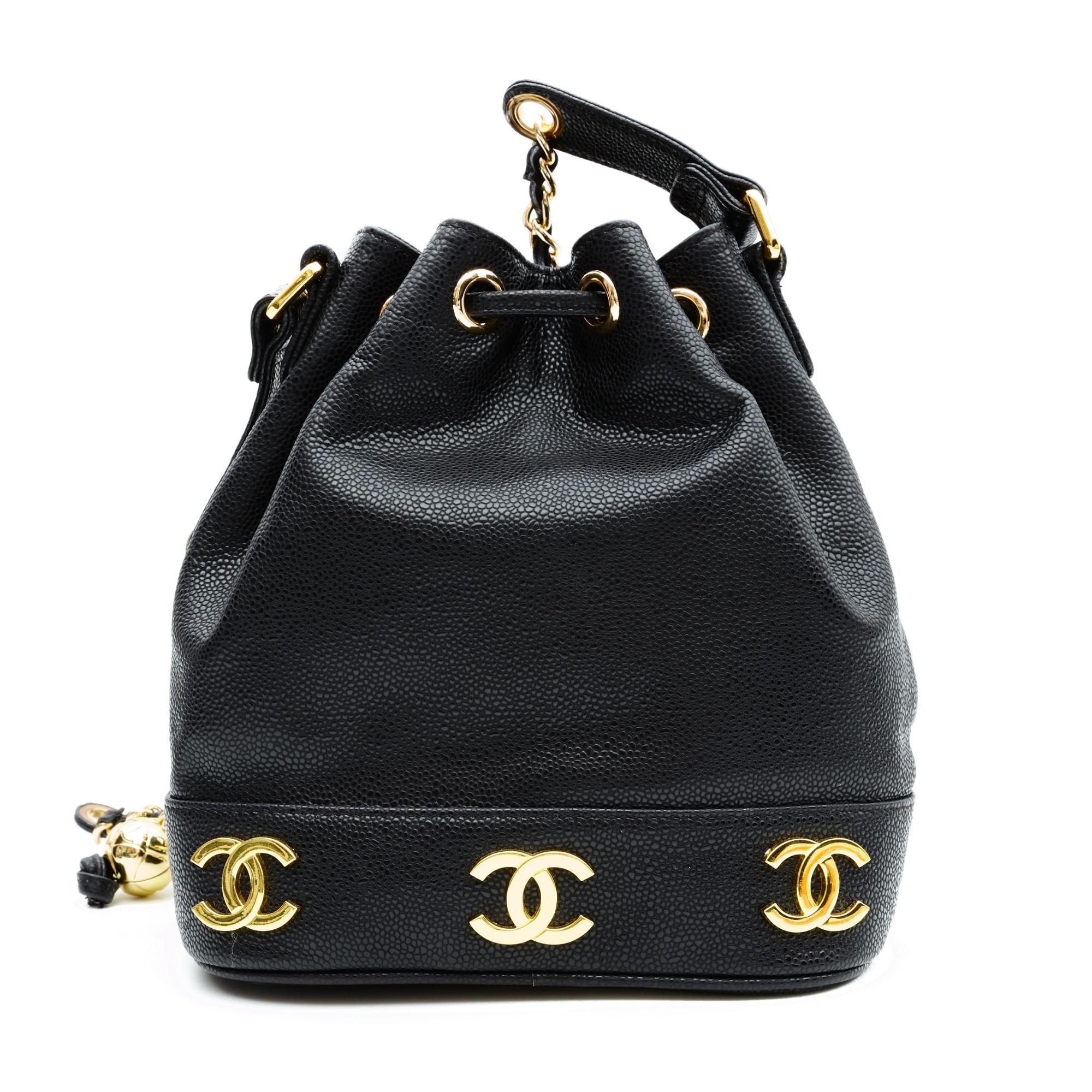 This bag is made with fine caviar leather structured in a bucket shape. The bag features the Chanel logo in gold tone around the base, a gold tone chain interlaced with leather, a leather shoulder pad, a leather pull cord for closure and a black