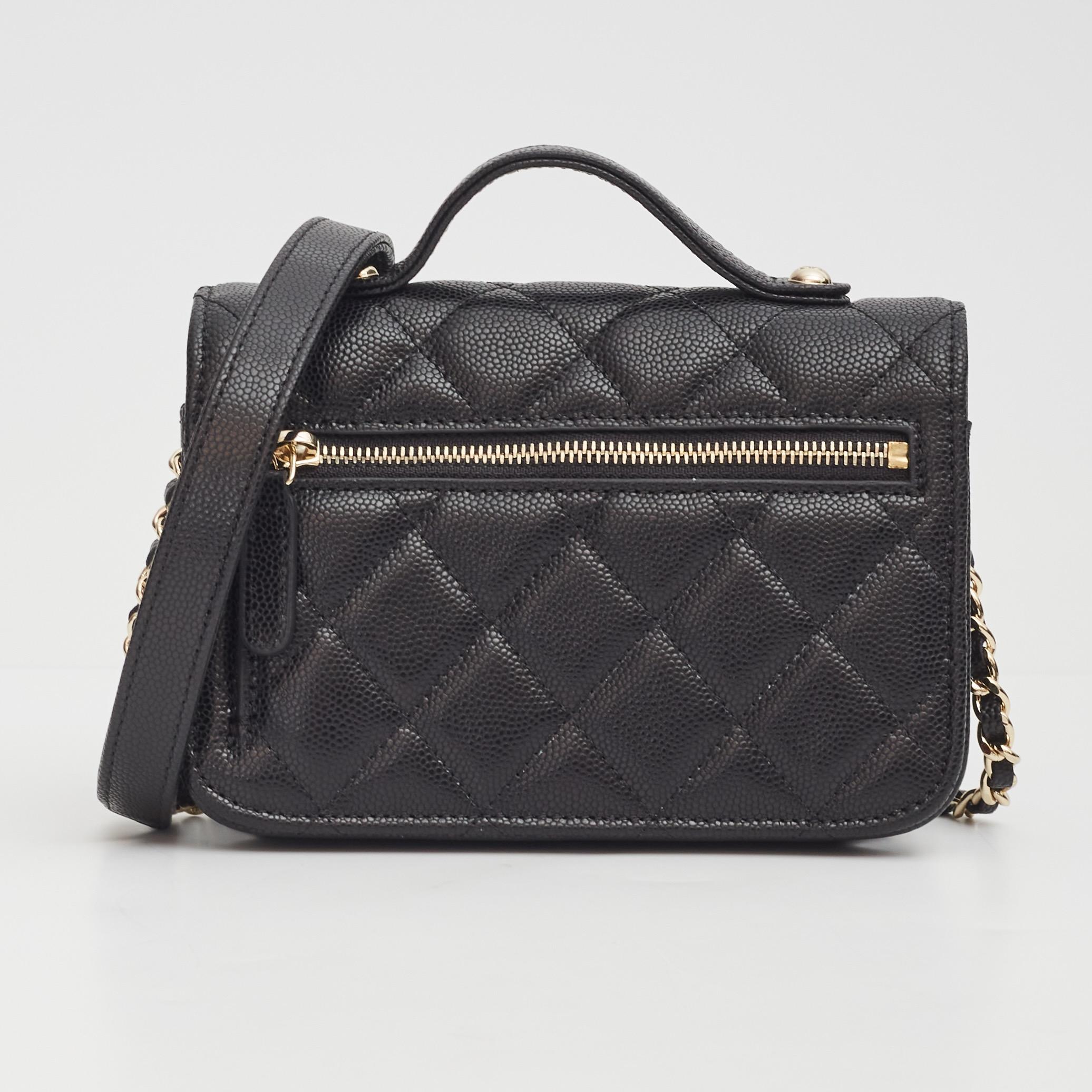 This classic Chanel bag is made with black caviar leather. The bag features a sturdy black leather top handle, a signature interlocking CC logo at face, a shoulder strap of a light gold tone chain interlaced with leather, a rear zip pocket and a