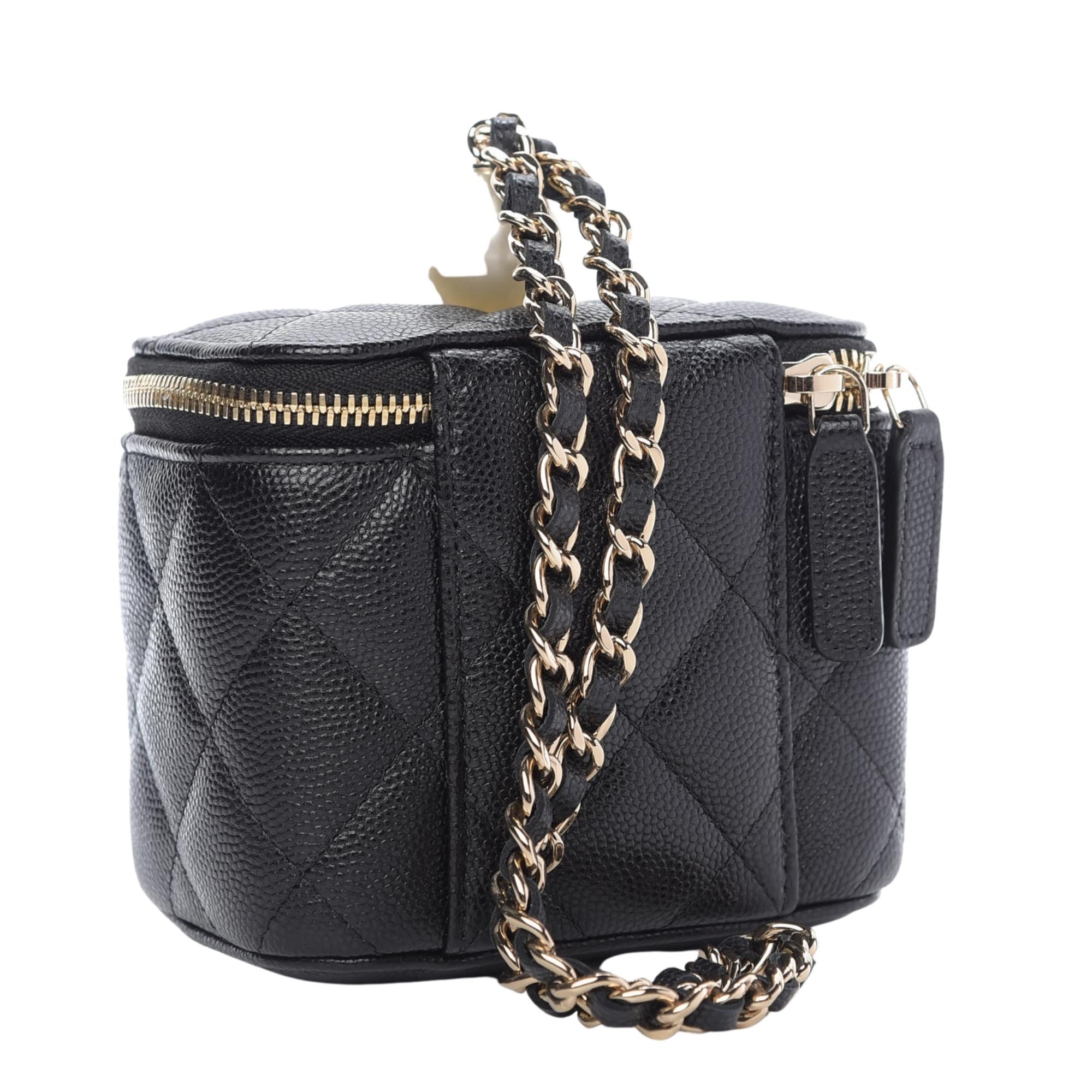 This mini vanity case is made of luxurious caviar leather in black. The bag features a gold chain-link interlaced with leather strap, gold hardware, a resin pearl at top and a 3/4 wrap-around zipper that opens to a black fabric interior. Chanel bags