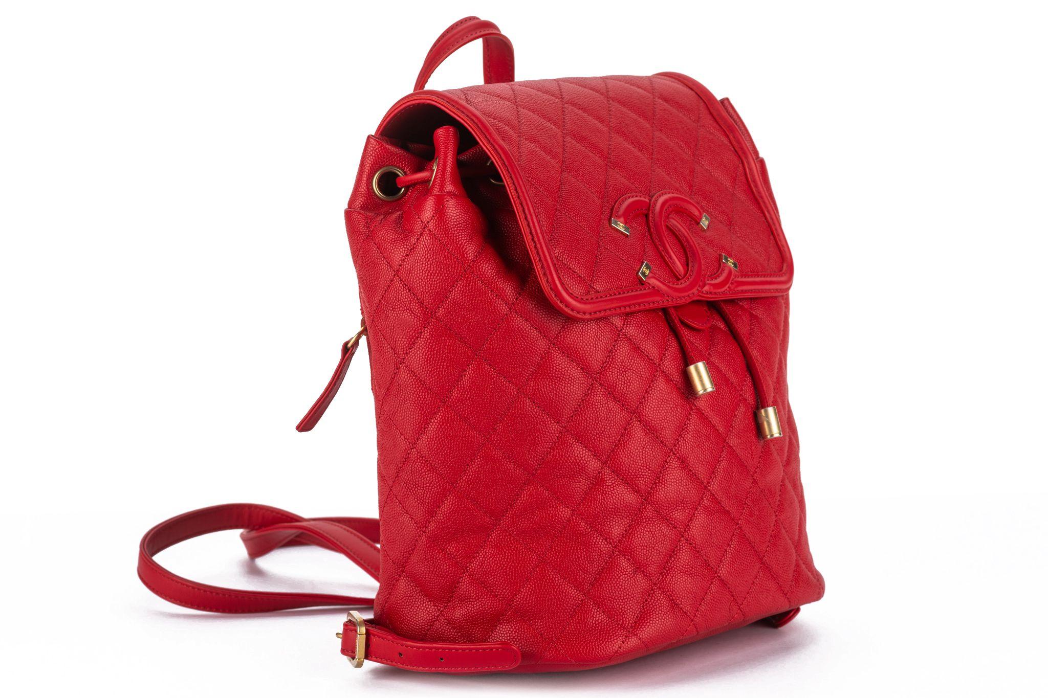This Chanel Caviar Quilted Filigree Backpack features beautiful caviar leather in red and an aged gold chain link leather threaded shoulder straps, a rear zippered pocket, and a crossover top flap accented by a quilted CC with gold tips. The top