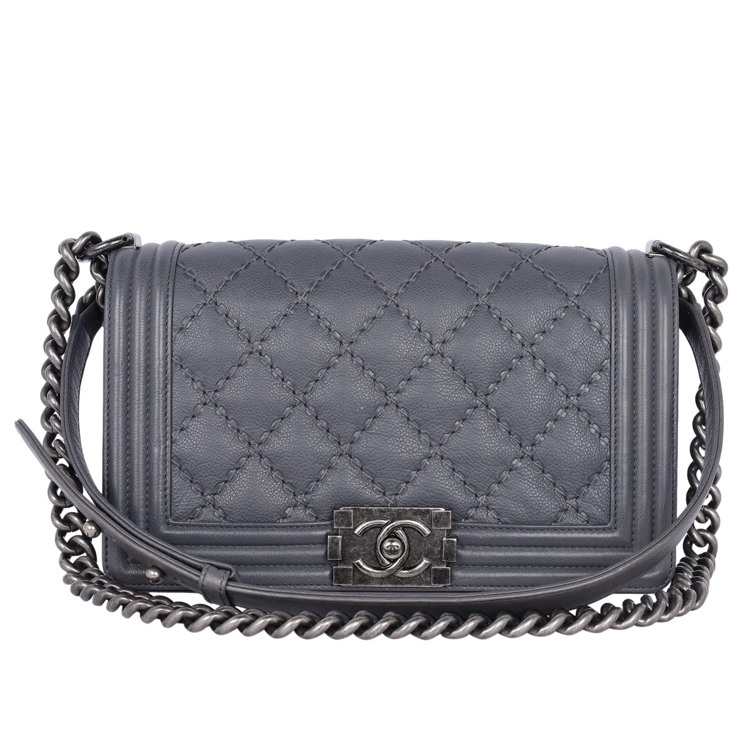 Authentic, pre-owned Chanel grey leather quilted caviar boy bag.

Features grey quilted caviar leather, large interlocking CC logo closure, long silver link chain strap with shoulder guard, interior zipper, and patch pocket. The long leather and