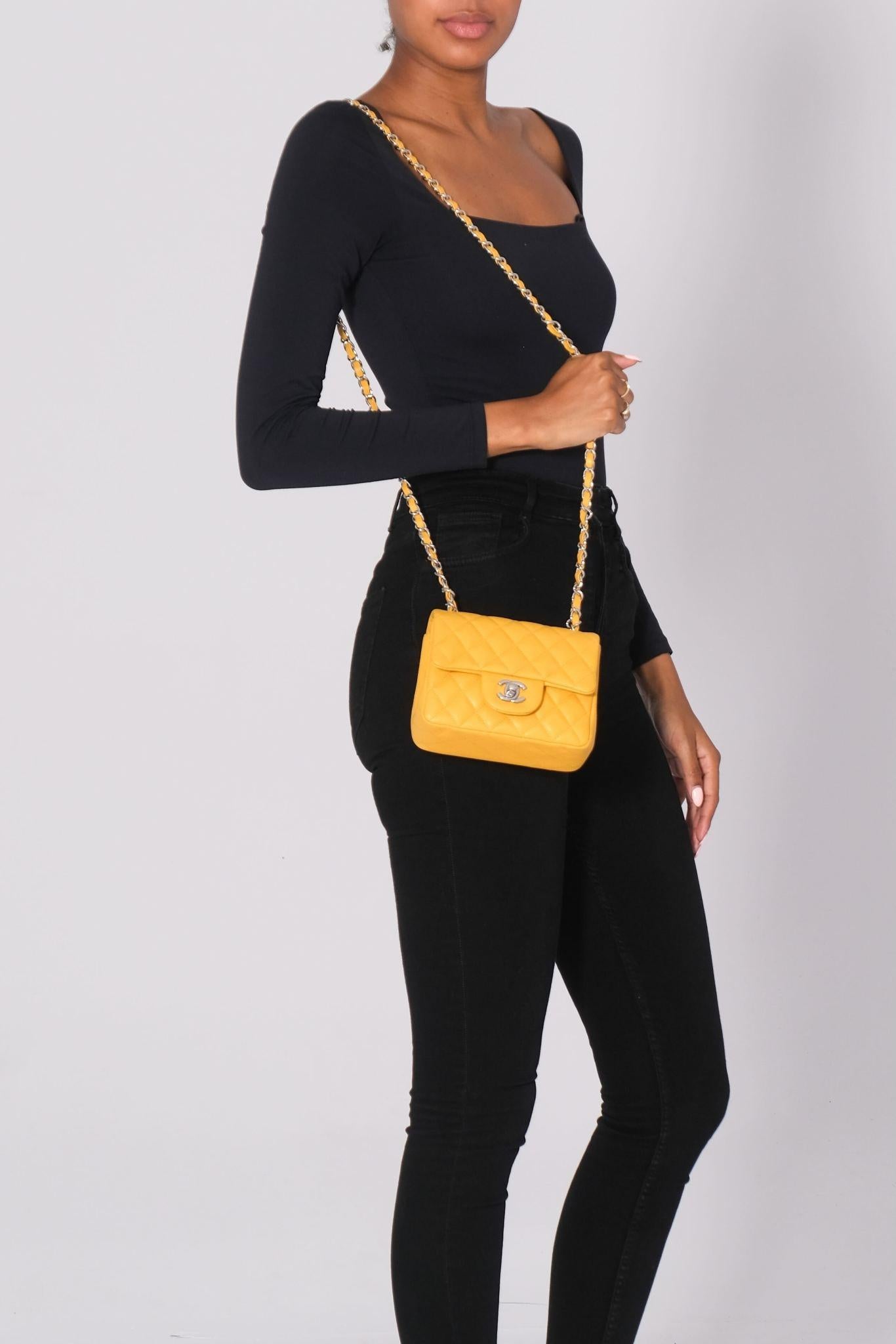 This classic Chanel mini square flap bag is constructed of caviar calfskin leather in yellow with silver hardware. The bag features a front flap, a back slip pocket, signature interlocking CC turn-lock closure and diamond quilting. The long chain