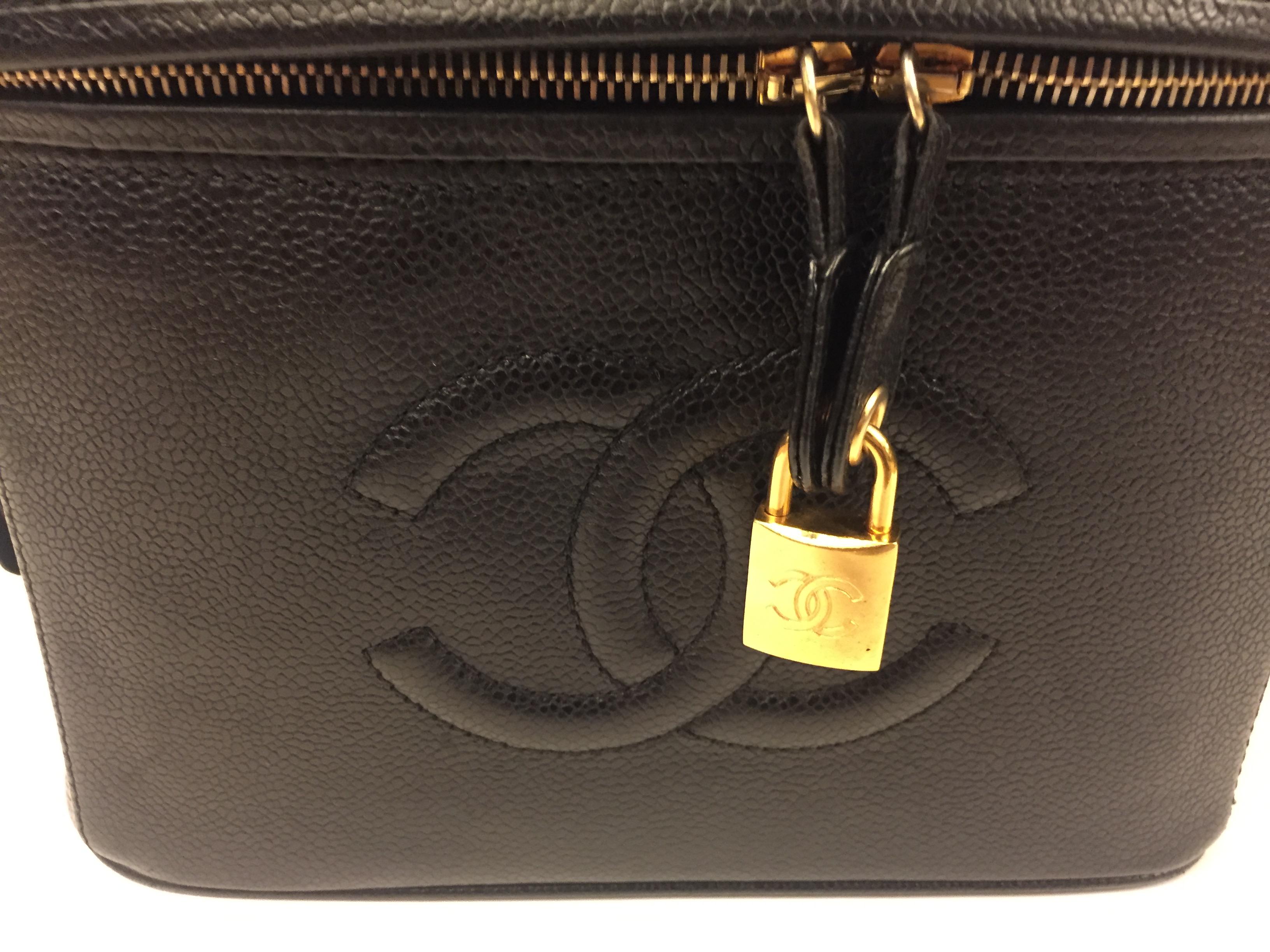 - Vintage 90s Chanel black caviar vanity bag. “CC” logo in front. 

- Zip closure and gold lock with key. 

- Interior with compartments. 

- Measurements: 24cm x 17cm x 16cm. Drop handle: 3cm. 

