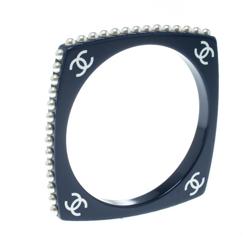Beautifully sculpted from resin, this Chanel bangle bracelet is a choice of a stylish woman. It carries a simple square design with faux pearls and the CC logos detailed on it. This bracelet is lovely and will be a fine outfit enhancer.

Includes:
