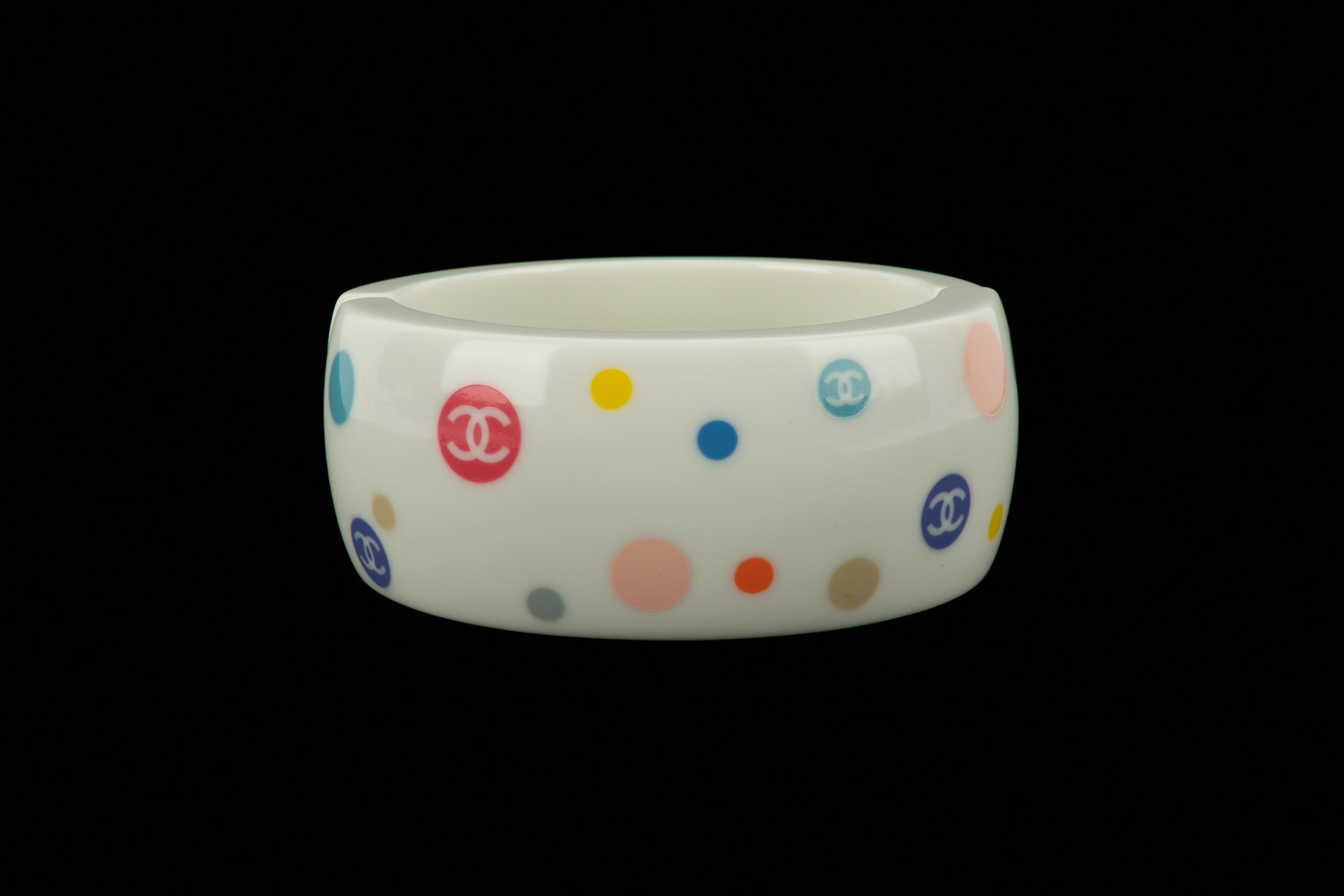 CHANEL - (Made in France) White bakelite bracelet ornamented with multicolored cc logos. 2005 Cruise Collection under the artistic direction of Karl Lagerfeld.

Condition:
Very good condition

Dimensions:
Circumference: 16.5 cm - Width: 3