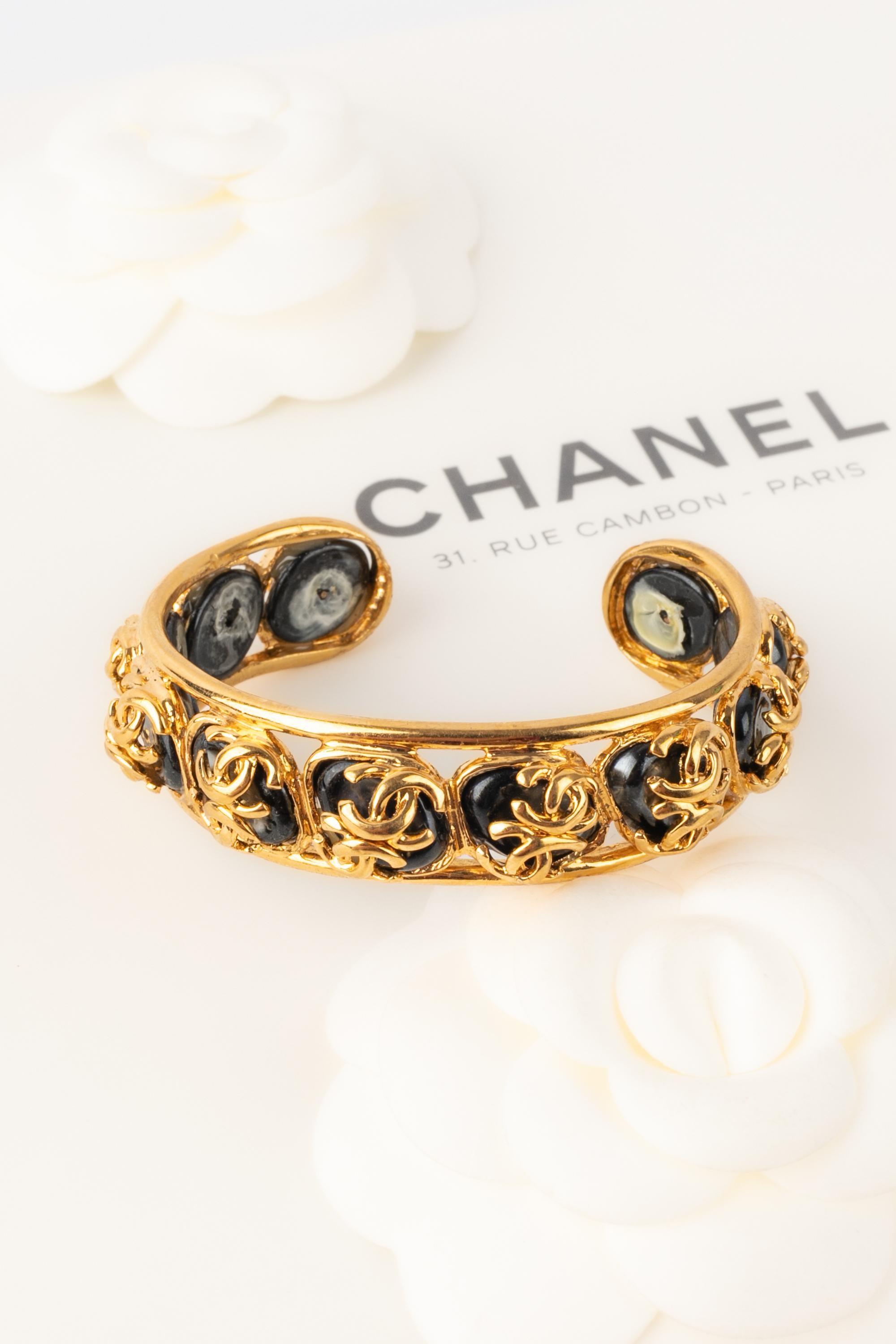 CHANEL - (Made in France) Golden metal rigid bracelet with grey pearlised cabochons. 1995 Fall-Winter Collection under the direction of Karl Lagerfeld.

Condition:
Very good condition

Dimensions:
Total circumference: 13 cm - Width: 2.5