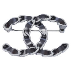 Broche Chanel CC de metal plateado y efecto cuero entretejido
