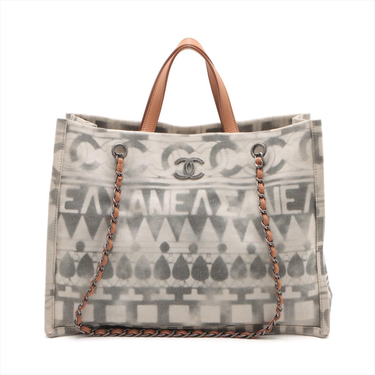 The Chanel CC Canvas & Leather Chain Tote Bag in Gray and White is a sophisticated and iconic accessory that seamlessly blends luxury and functionality. Crafted from durable canvas and supple leather. The gray and white color palette exudes