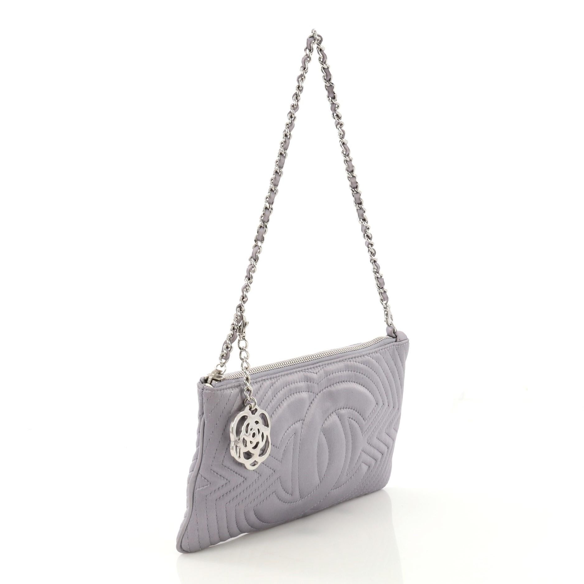 This Chanel CC Chain Clutch Stitched Satin, crafted in purple quilted satin, features a woven in leather chain-link strap, Camellia charm and silver-tone hardware. Its zip closure opens to an off-white fabric interior with slip pocket. Hologram