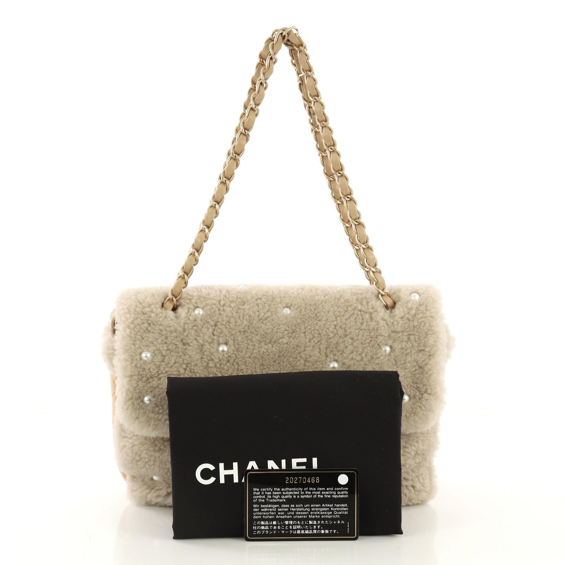 This Chanel CC Chain Flap Bag Pearl Embellished Shearling Medium, crafted from beige pearl embellished shearling, features woven-in leather chain strap, exterior back slip pocket, and matte gold-tone hardware. Its CC turn-lock closure opens to a