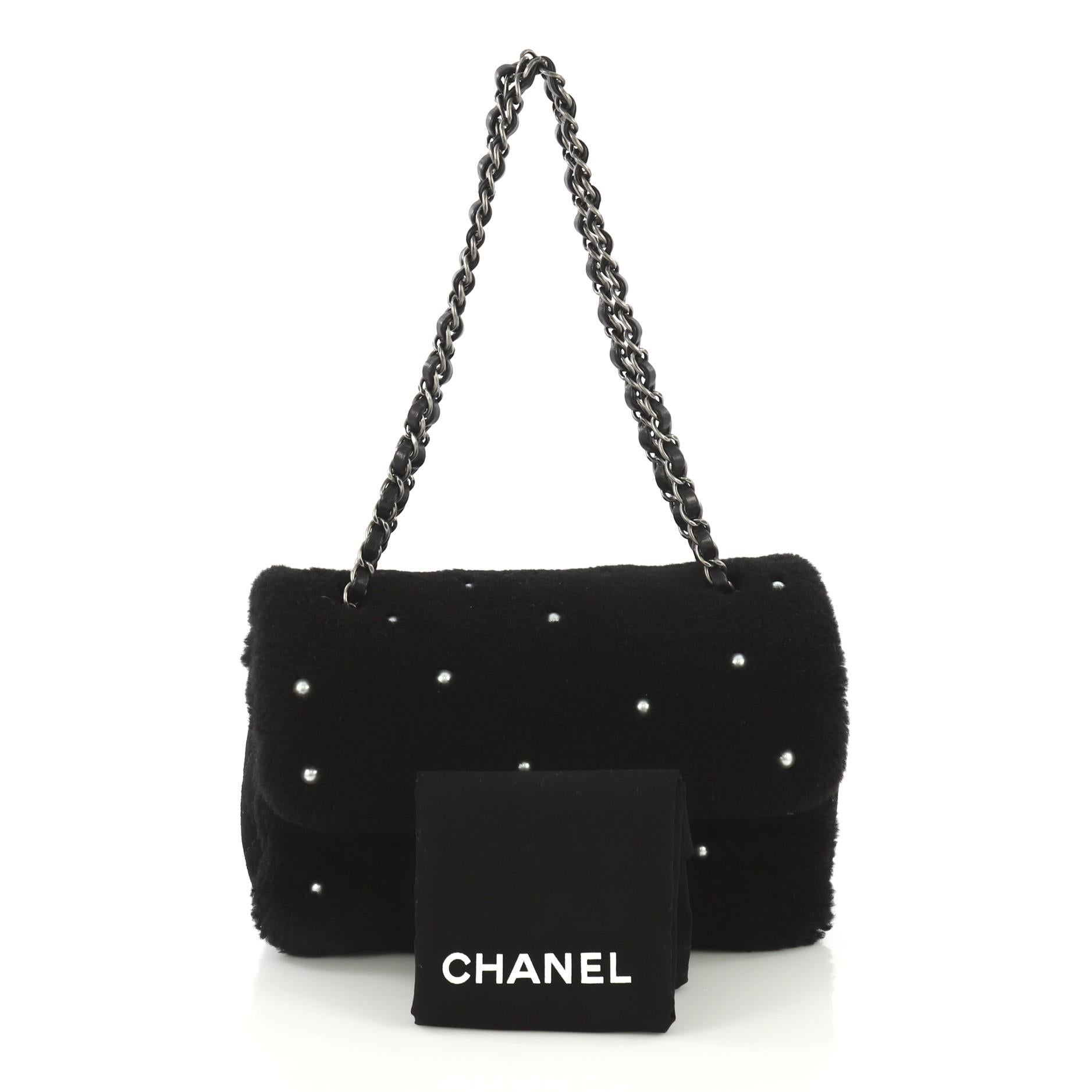 This Chanel CC Chain Flap Bag Pearl Embellished Shearling Medium, crafted from black pearl embellished shearling, features woven-in leather chain strap, exterior back slip pocket, and aged silver-tone hardware. Its CC turn-lock closure opens to a