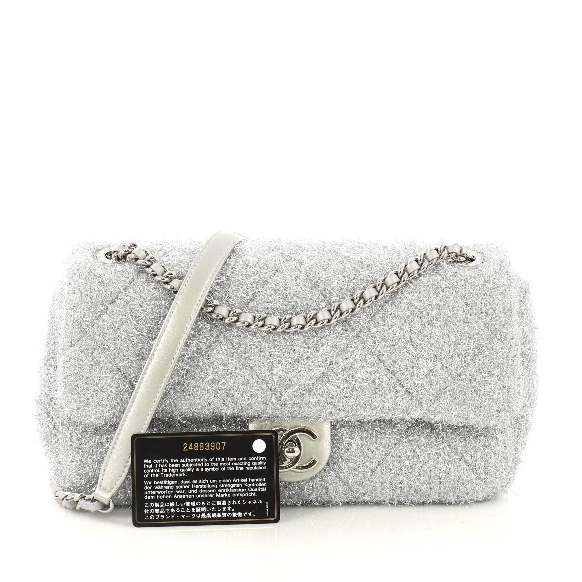 This Chanel CC Chain Flap Bag Quilted Knit Pluto Glitter Medium, crafted in silver quilted knit pluto glitter, features woven-in knit chain strap, and silver-tone hardware accents. Its CC turn-lock closure opens to a light blue satin interior with