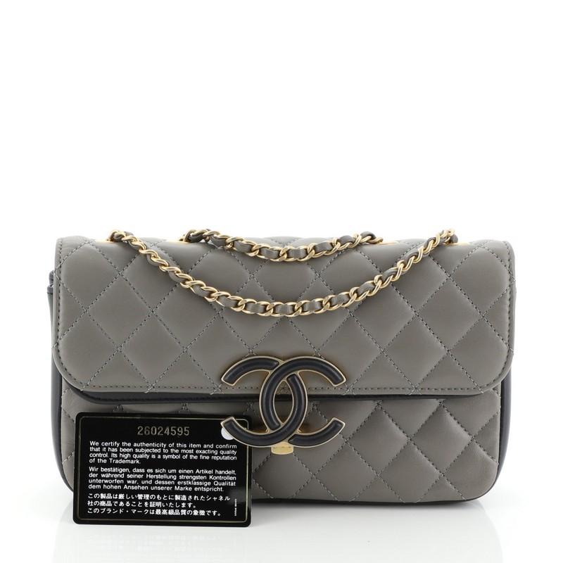 This Chanel CC Chic Double Flap Bag Quilted Lambskin Small, crafted in gray leather, features woven- in leather chain strap, large enamel CC Clasp and aged gold-tone hardware. Its clasp closure opens to a two-compartment gray leather interior.