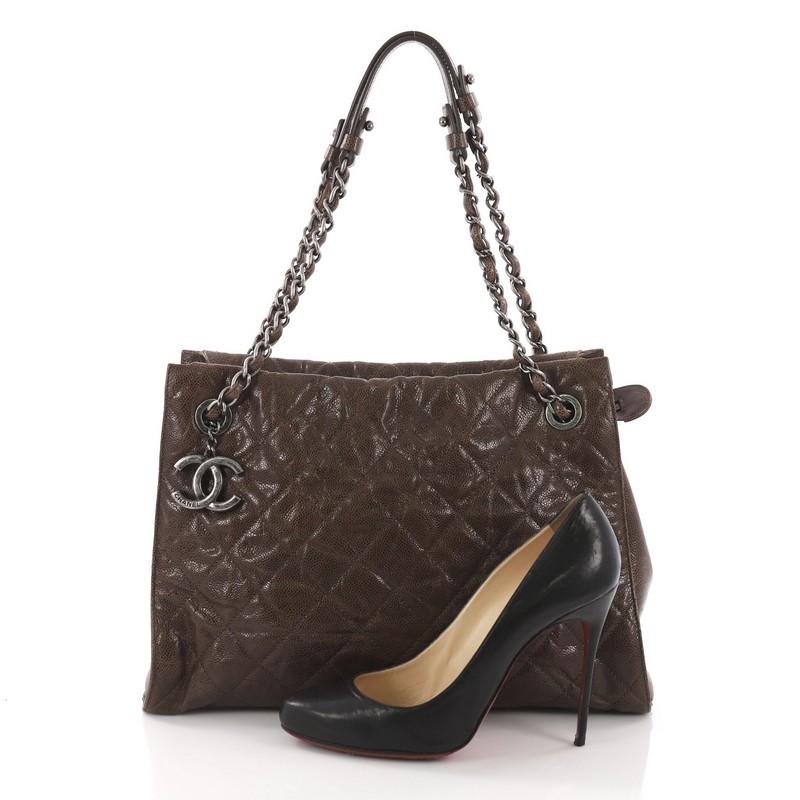 This Chanel CC Crave Shoulder Bag Quilted Glazed Caviar Medium, crafted from brown quilted glazed caviar leather, features woven-in leather chain with leather shoulder pads, CC logo charm, and aged silver-tone hardware. It opens to a maroon fabric