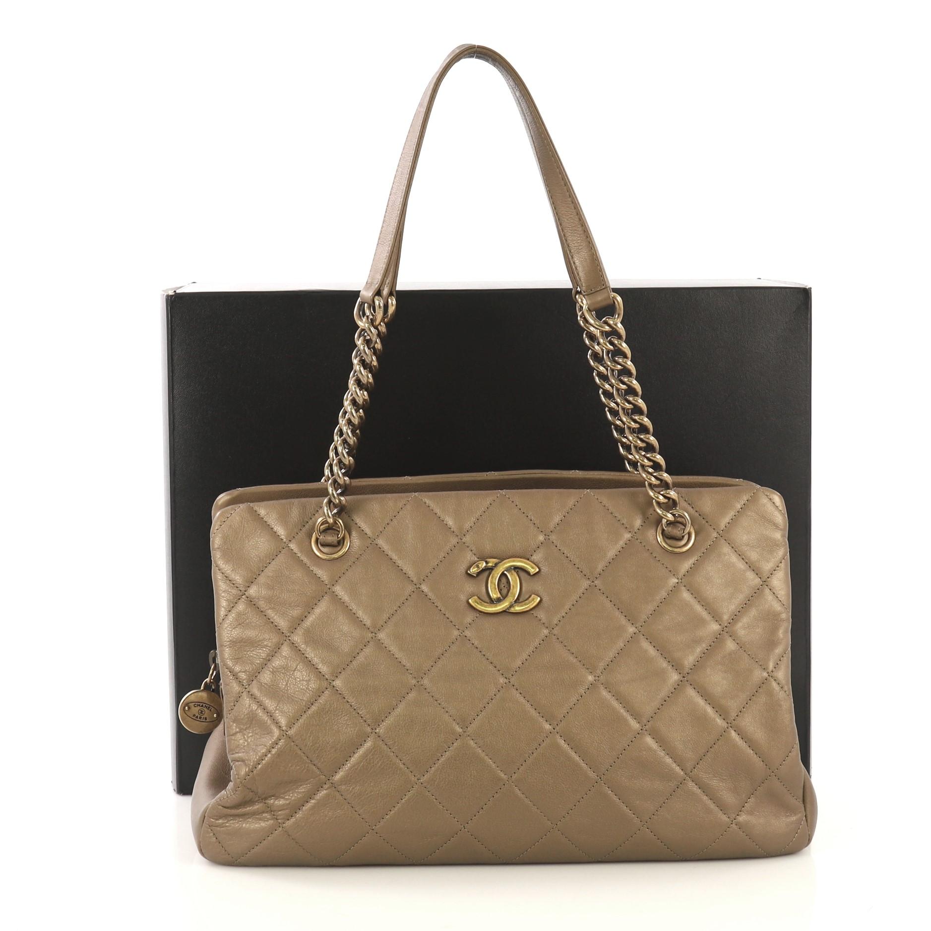 This Chanel CC Crown Tote Quilted Leather Medium, crafted from dark gold quilted leather, features chain straps with leather pads, protective base studs, and aged gold-tone hardware. It opens to a beige fabric interior divided into two open