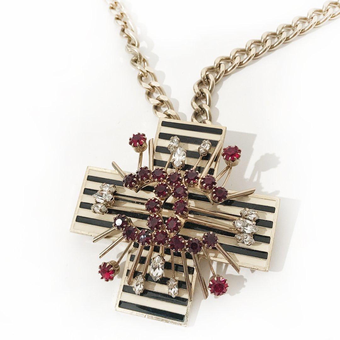 CC Crystal Cross Necklace by Chanel
Fall 2005
Gold-tone hardware
Navy and ivory striped enamel cross 
Dark red CC crystal center
Clear and red crystal starburst detail surrounding center
Navy and ivory striped CC charm on necklace back
Lined by