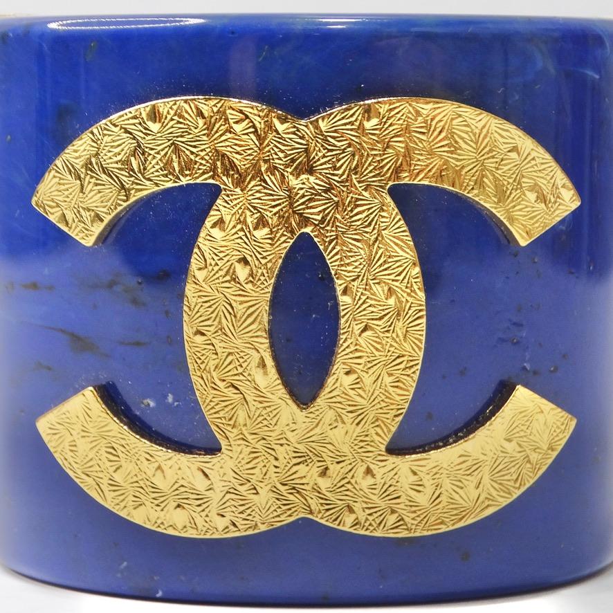 Do not miss out on this absolutely show stopping Chanel cuff bracelet! A vibrant blue marble look resin comes together with gold tone metal to create this whimsical statement bracelet! The star of the show is the signature Chanel gold tone