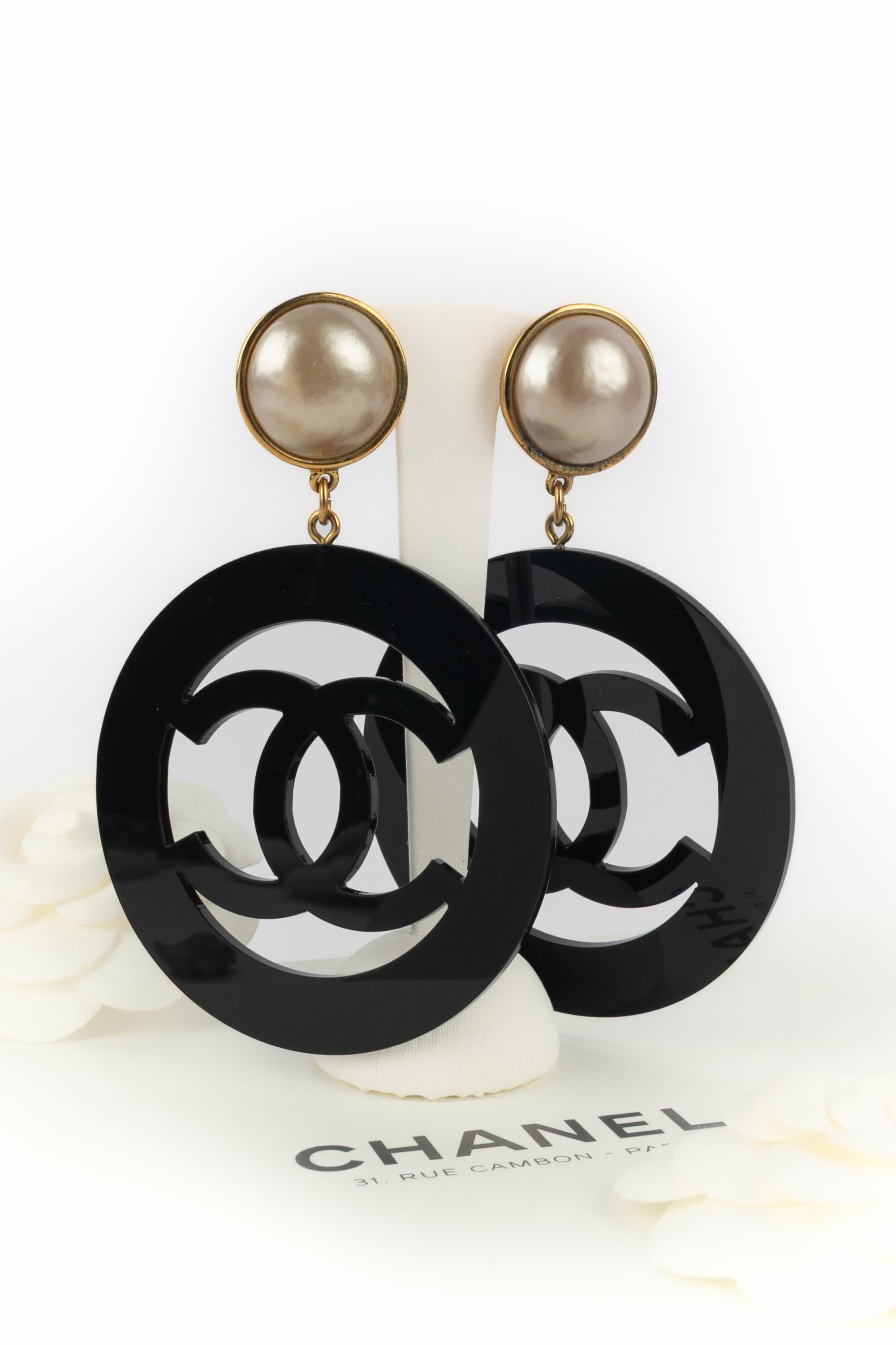 Chanel - (Made in France) Orecchini a clip in metallo dorato con un pendente in bachelite nera. Una collezione 2cc8 dei primi anni '90 sotto la direzione artistica di Karl Lagerfeld.

Condizioni:
Ottime condizioni

Dimensioni:
Lunghezza: 12