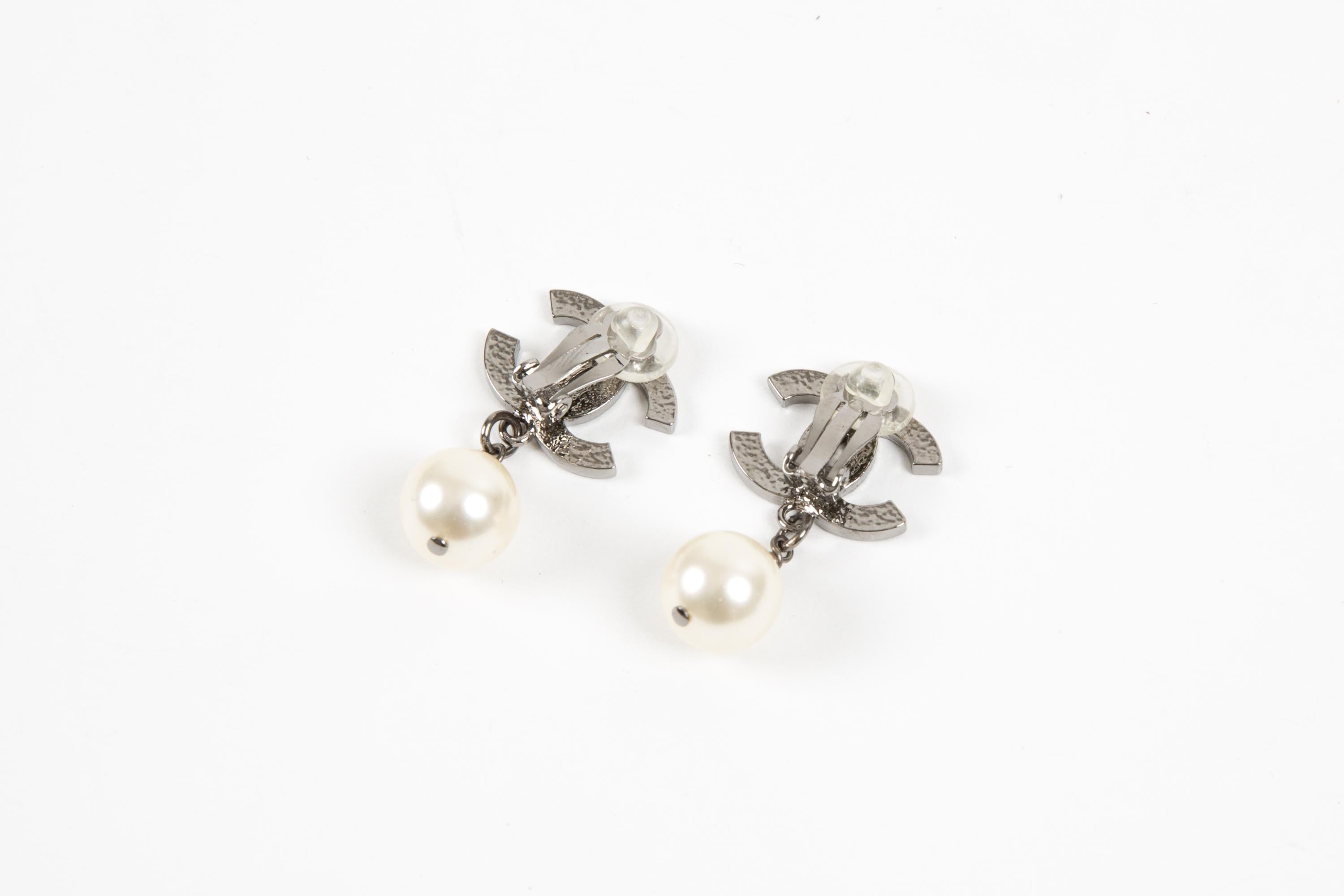 Chanel CC faux-pearl clip-on earrings featuring silver-tone signature interlocking CC logo, ivory faux-pearl embellishment,  a clip-on design, back plaque pitted. They come as a pair. 
Circa 2010 
Good vintage condition. Made in France.   
Length:
