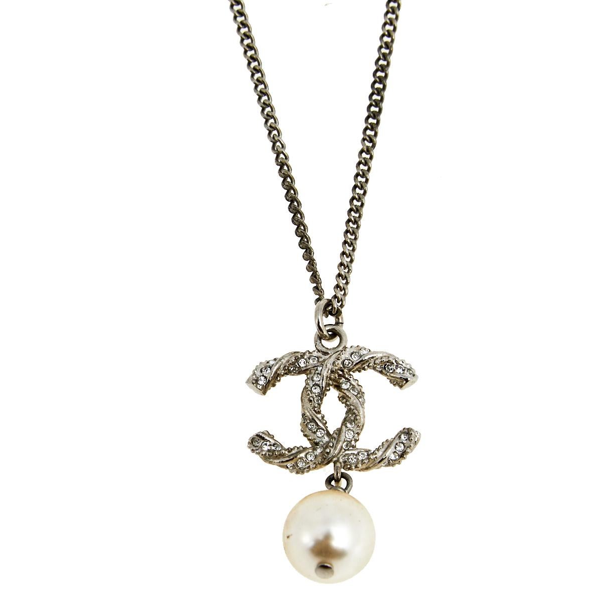 From the house of Chanel, this classic piece is designed with a chain secured by a lobster clasp closure. It features a twisted, interlocked 'CC' logo pendant enhanced with crystal embellishments and accompanied by faux pearl drop. Wear with blouses