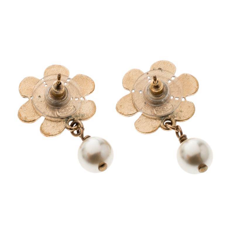 The embellished Camellia motif accented with CC logos enhanced by an elegant faux pearl makes this pair of Chanel earrings an accessory to embrace the glamorous look. Crafted exquisitely with luxe gold-tone metal that imparts a graceful élan to your