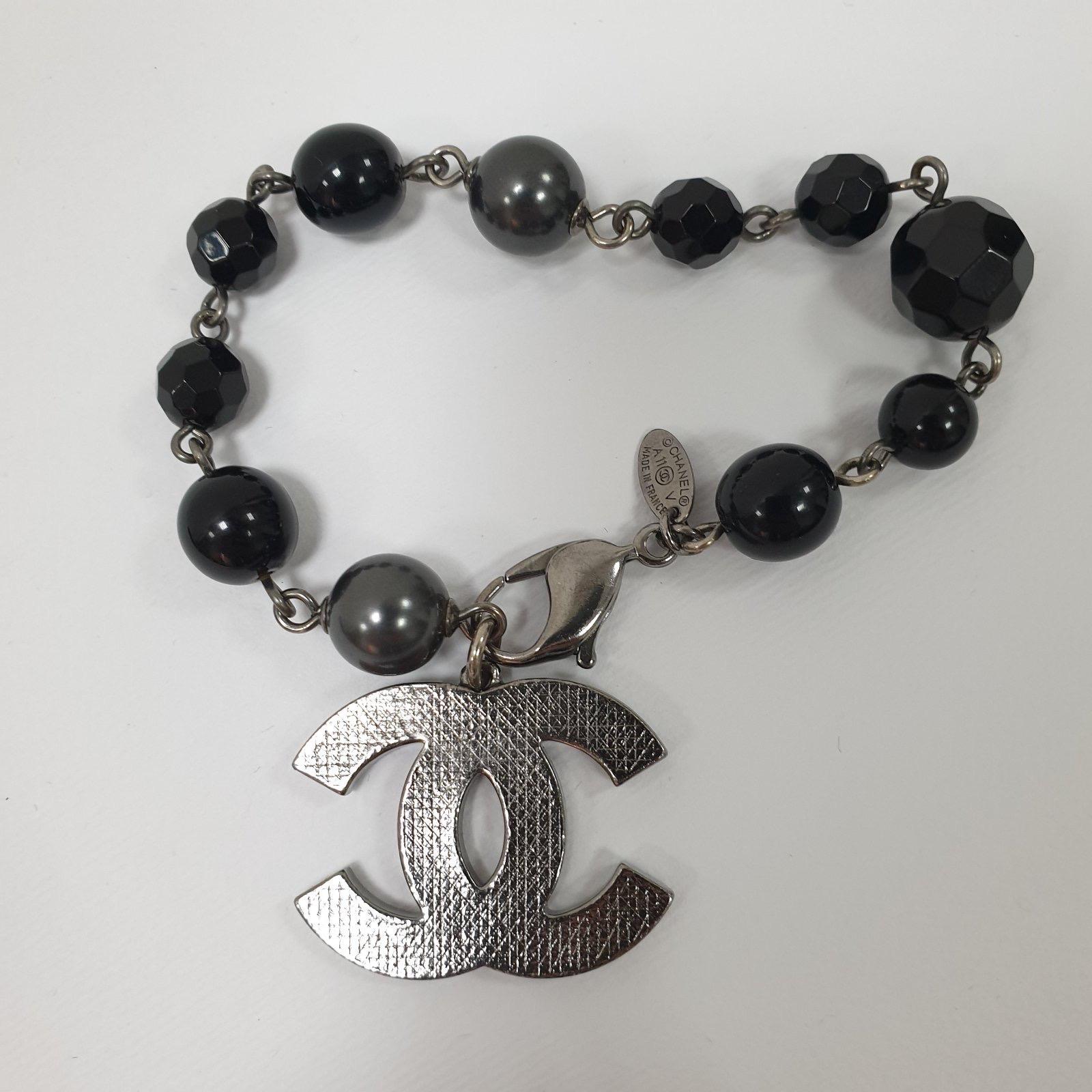 Herbst 2011
Dieses Chanel-Armband aus silberfarbenem Metall ist niedlich und zierlich. Es besteht aus schwarzen und grauen Perlen, die mit einem ineinandergreifenden CC-Charme kombiniert sind. Sie ist mit einem Karabinerverschluss