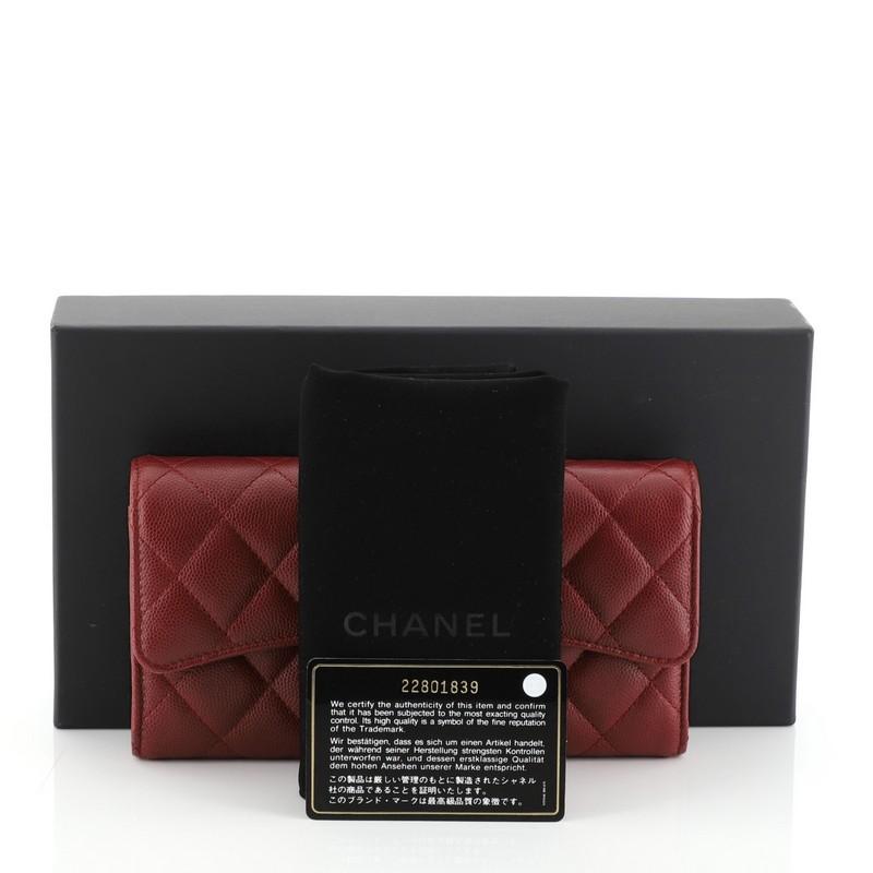 This Chanel CC Gusset Classic Flap Wallet Quilted Caviar Long, crafted from red quilted caviar leather, features interlocking CC logo, gusseted sides, and aged silver-tone hardware. Its snap button closure opens to a red fabric interior with