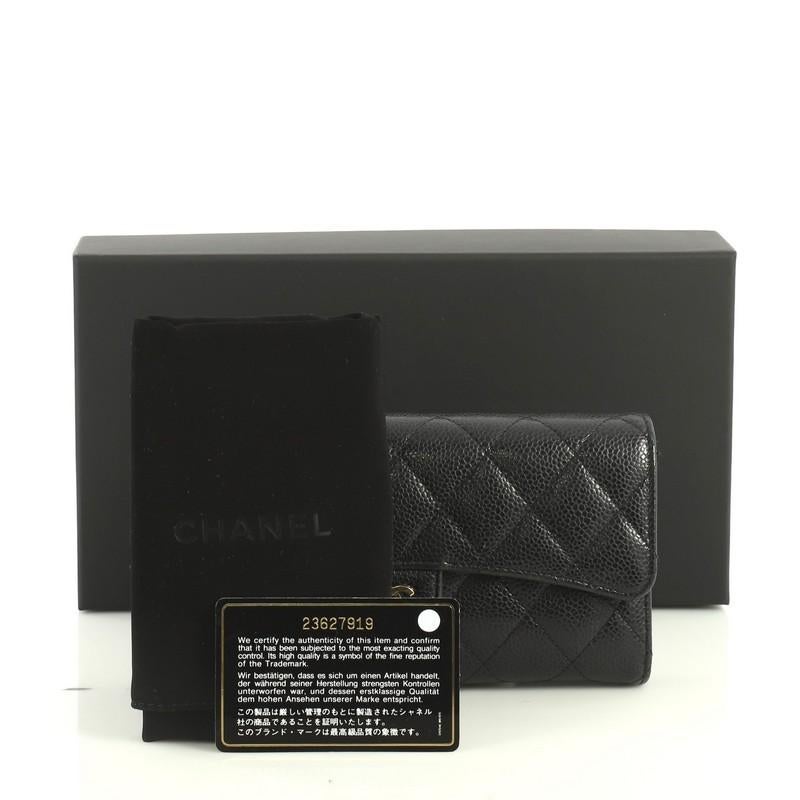 This Chanel CC Gusset Classic Flap Wallet Quilted Caviar Long, crafted from black quilted caviar leather, features interlocking CC logo, gusseted sides, and gold-tone hardware. Its snap button closure opens to a red leather and fabric interior with