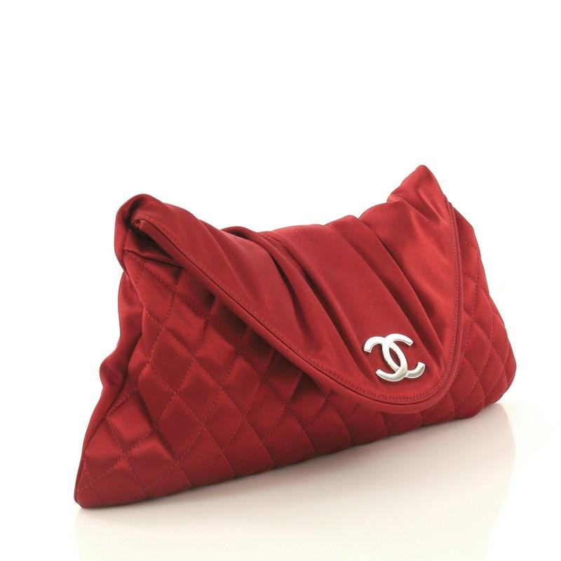 This Chanel CC Half Moon Clutch Quilted Satin Large, crafted in red quilted satin, features frontal CC logo and gunmetal-tone hardware. Its magnetic snap closure opens to a white satin interior with slip pocket. Hologram sticker reads: 11925209.