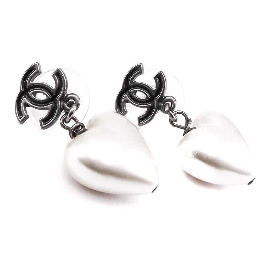CHANEL pearly heart studs

The earrings are studs created by Maison CHANEL. They have a CC in black enamel and metal at the level of the nail on which a pearly heart swings. 
The earrings are in very good condition. Presence of a micro-scratch on