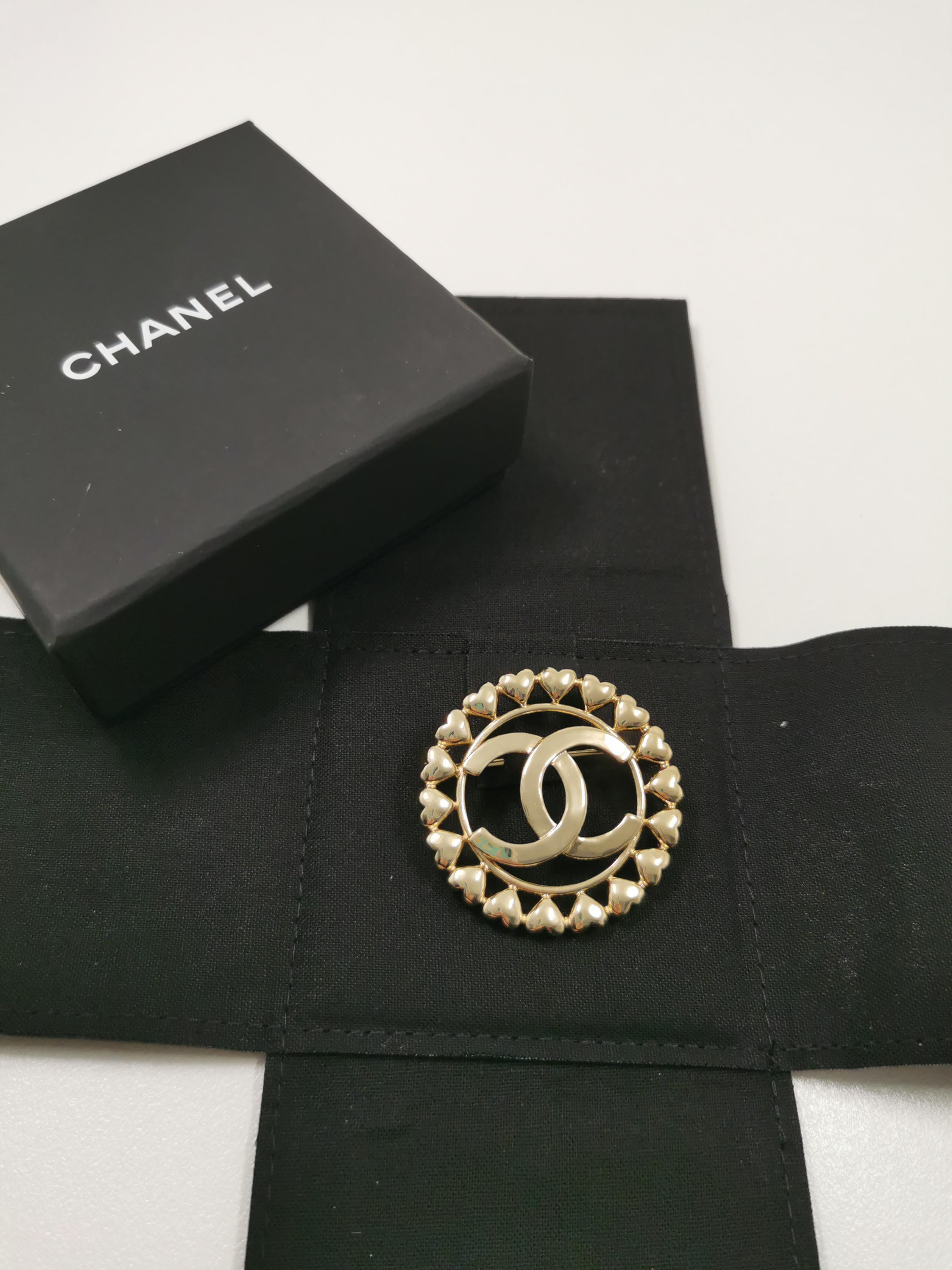 Introducing the epitome of grace and sophistication – the Chanel CC Large Round Brooch with Mini Heart Border from the Spring-Summer 2023 collection. This exquisite brooch encapsulates the essence of Chanel's iconic design language while adding a