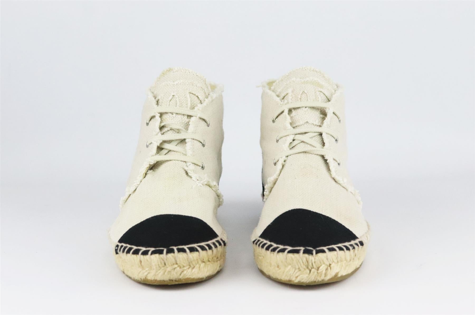 Chanel's lace-up espadrilles in cream linen, featuring the brand's trademark interlocking CC logo on the tongue in a matching frayed cream linen, they have a thick jute sole and a reinforced canvas toe which offers a comfortable and supportive fit.