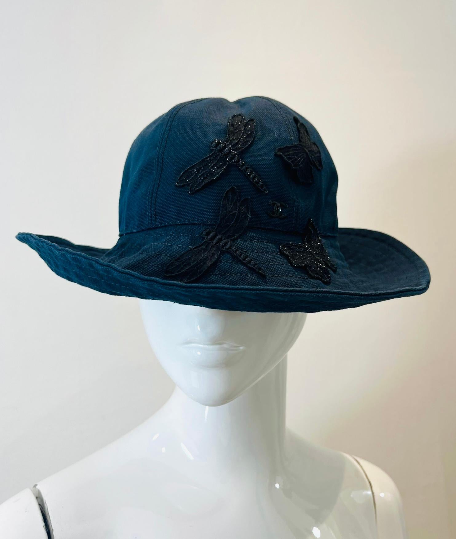 Chanel 'CC' Logo Butterfly Embellished Cotton Hat

Navy blue hat designed with black butterfly and dragonfly adornments accented with lace and sparkling silver threads.

Featuring black 'CC' logo detail and satin lined interior.

Size – 
