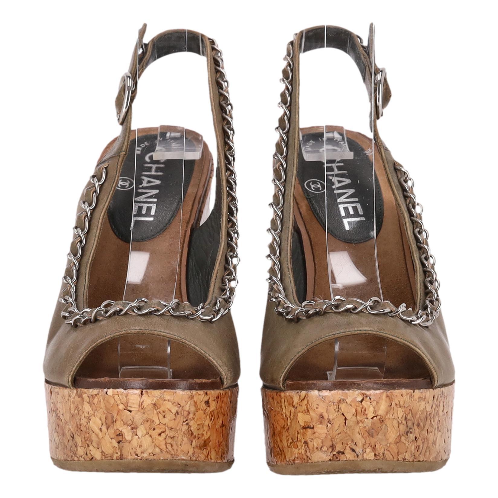 Chanel 'CC' Sandalias de cuña de corcho de piel con logotipo y detalle de cadena

Cuñas con puntera abierta de color caqui/marrón confeccionadas en piel y adornadas con un emblemático ribete de piel y cadena.

Con tacón de plataforma con cuña de