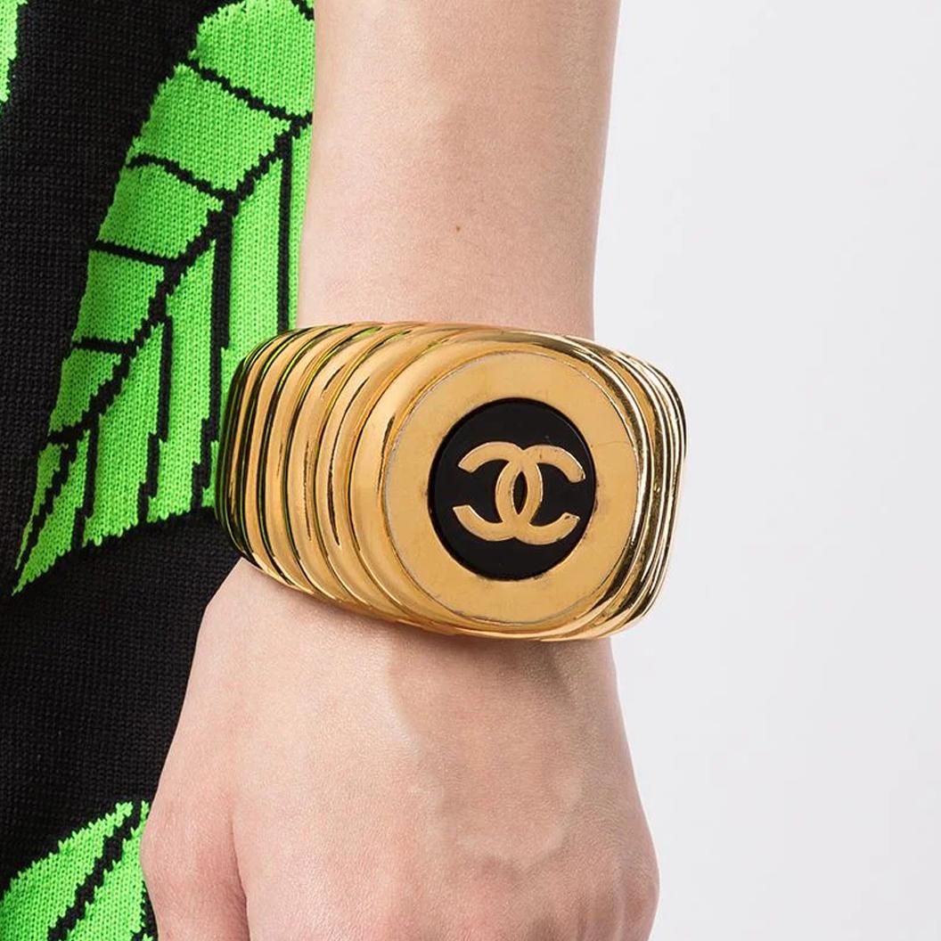 A statement piece, this bold and chunky vintage 1980s pre-owned Chanel cuff is a must-have piece in anyone's collection. The gold-tone bracelet features a ribbed design, with a jet-black disc in the centre enhanced by the iconic CC logo. Lay yours