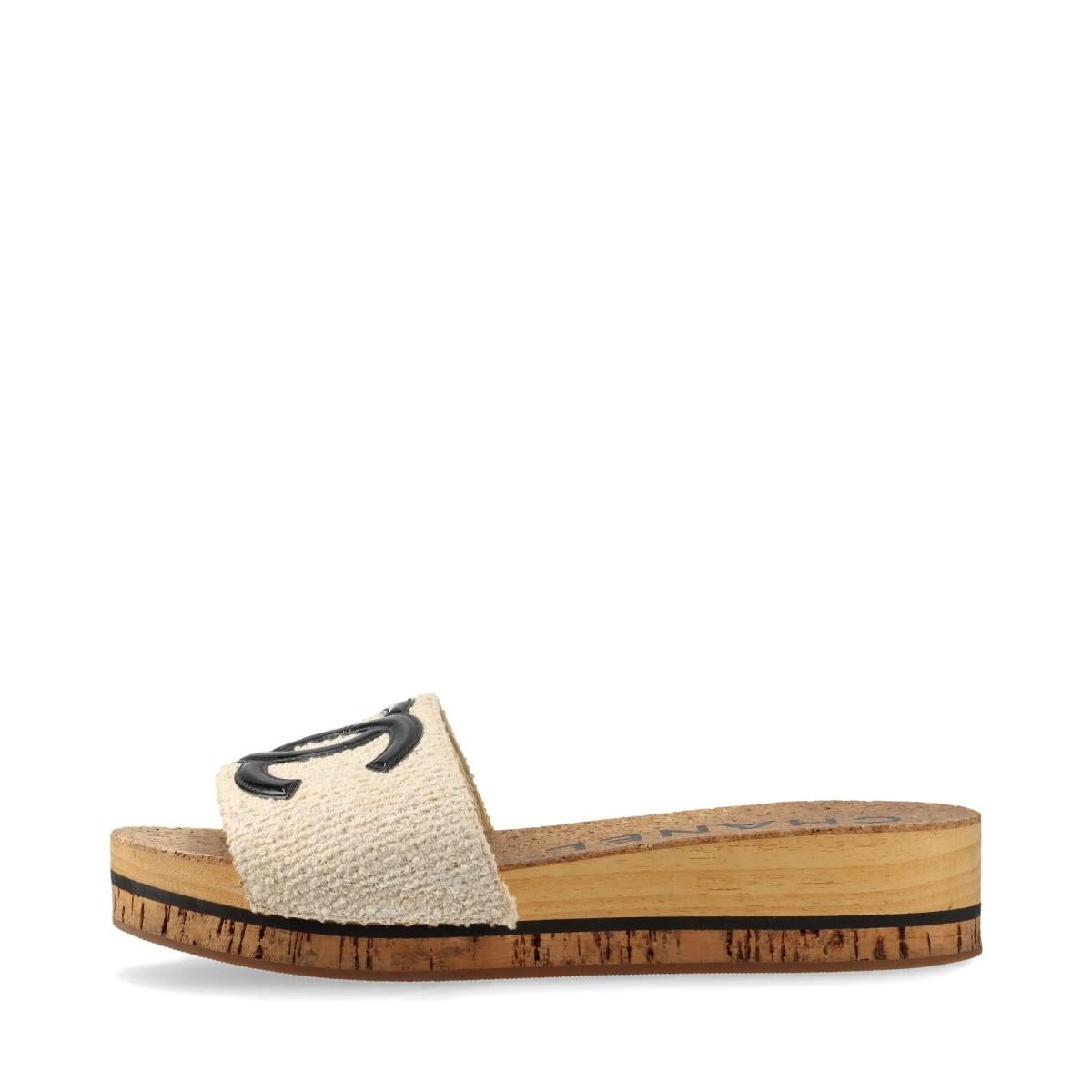 The Chanel CC Logo Fabric Wooden Sandal in Ivory and Brown is a sophisticated blend of elegance and natural charm. The sandal features a fabric upper adorned with the iconic CC logo, adding a touch of classic Chanel sophistication. The ivory fabric