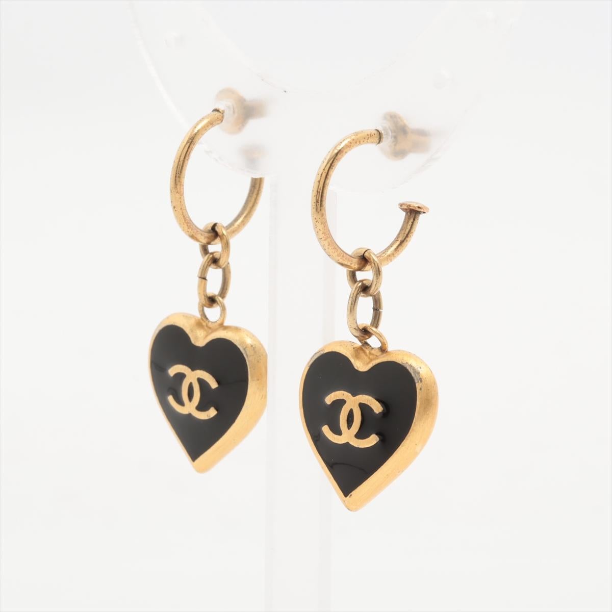 The Chanel CC Logo Heart Hoop Dangle Earring in Gold with Black Enamel is a stunning blend of elegance and charm. The earrings feature sleek gold-tone hoops adorned with delicate black enamel hearts and the iconic Chanel CC logo. The contrast