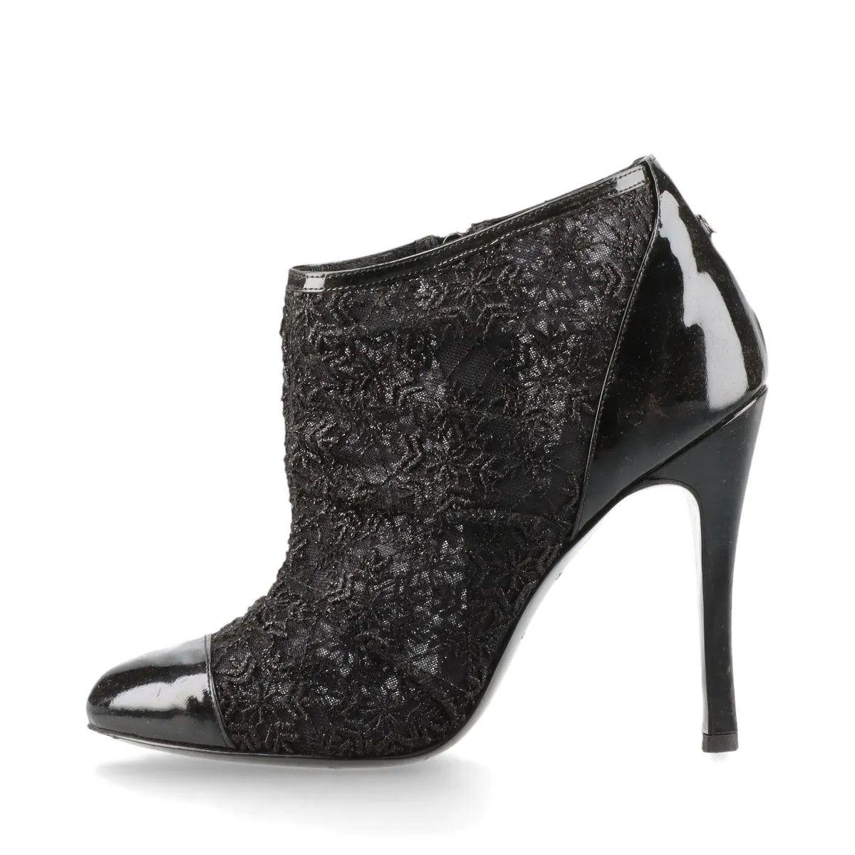 The Chanel CC Logo Lace x Patent Leather Pointed Heel Boots in Black are a sophisticated blend of elegance and edge. Crafted from intricate lace with glossy patent leather accents, the boots feature a sleek pointed toe and a refined low-cut