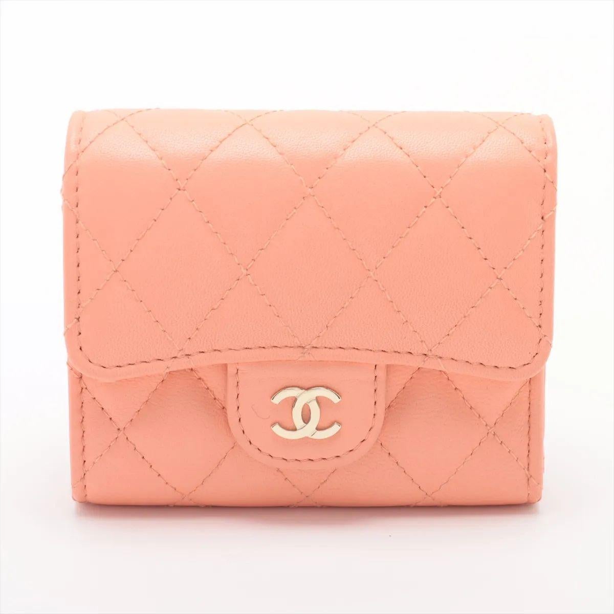 The Chanel CC Logo Matelassé Lambskin Compact Wallet in pink salmon is a charming blend of elegance and functionality. Crafted from luxurious lambskin leather, it features the signature diamond quilting that exudes timeless Chanel sophistication.