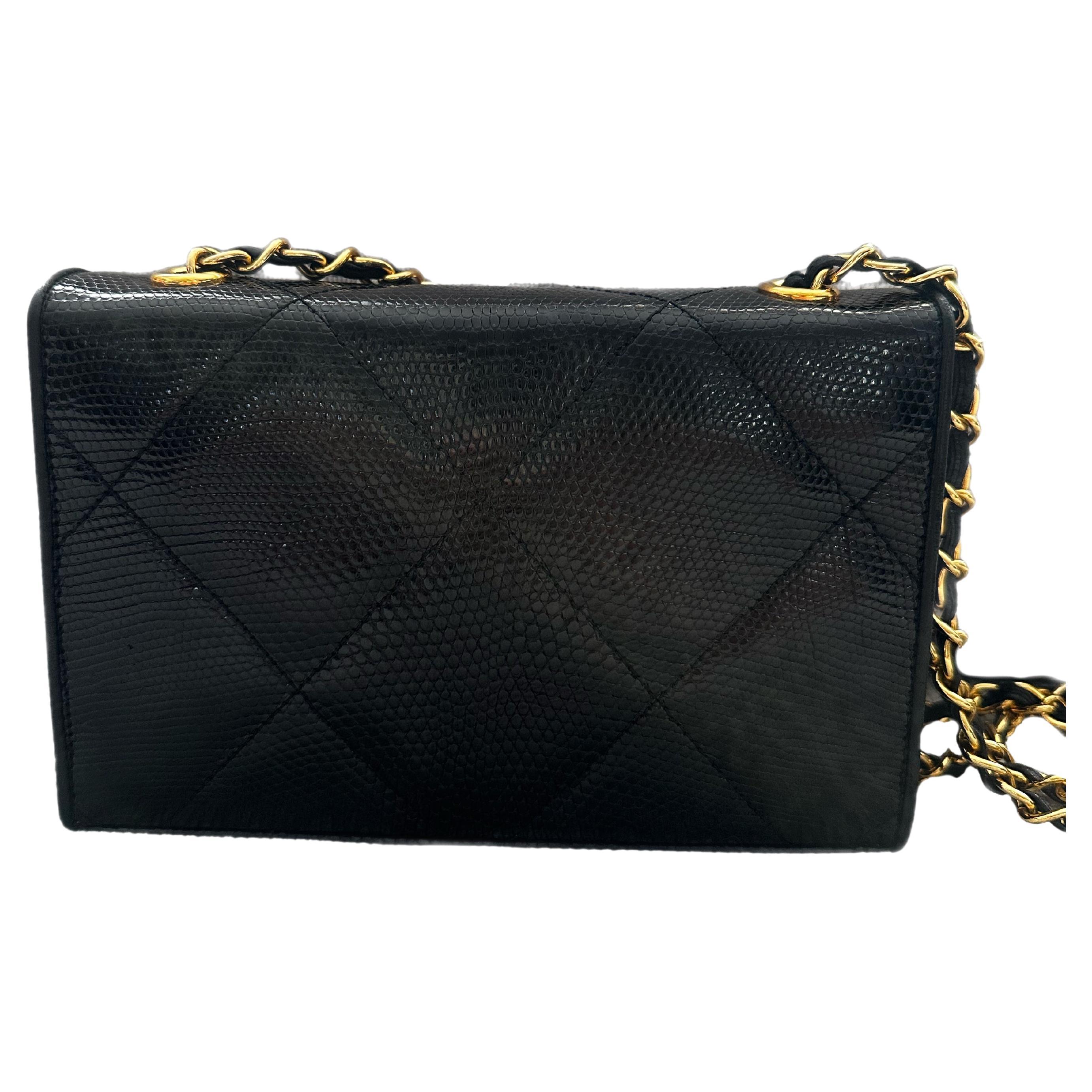 The Chanel CC Logo Matelassé Lizard Leather Chain Shoulder Bag in Black is a rare and luxurious statement piece. Crafted from exquisite lizard leather, the bag features signature Matelassé quilted pattern, adding texture and depth to its sleek