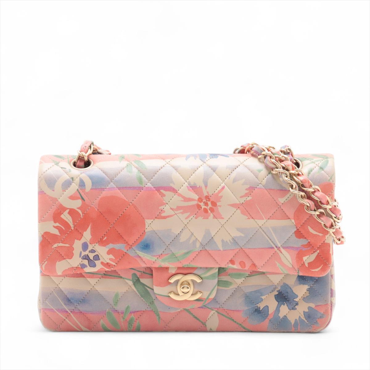 El Bolso Chanel CC Logo Multicolor Floral Acuarela con Solapa Doble de Piel de Cordero es una pieza llamativa y femenina, confeccionada en suave piel de cordero rosa adornada con un delicado estampado floral de acuarela. Con el icónico acolchado de