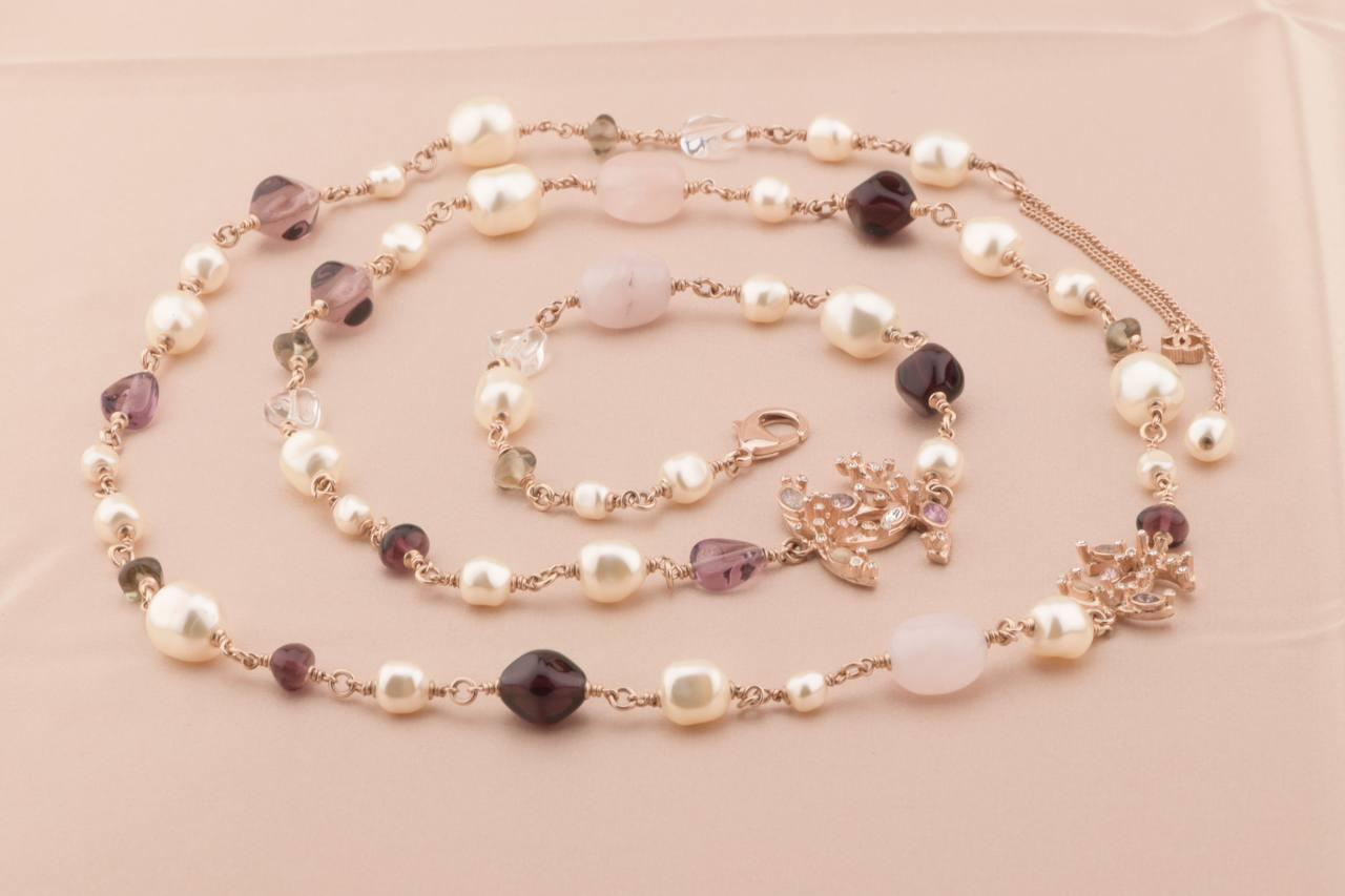 Chanel Pink/Purple Stone Faux Pearl and Crystal CC Long Necklace is a must-have accessory. This lovely necklace features rose goldtone CC logos inlaid with crystals and stones. The necklace has faux pearls and rose quartz and purple stones strung